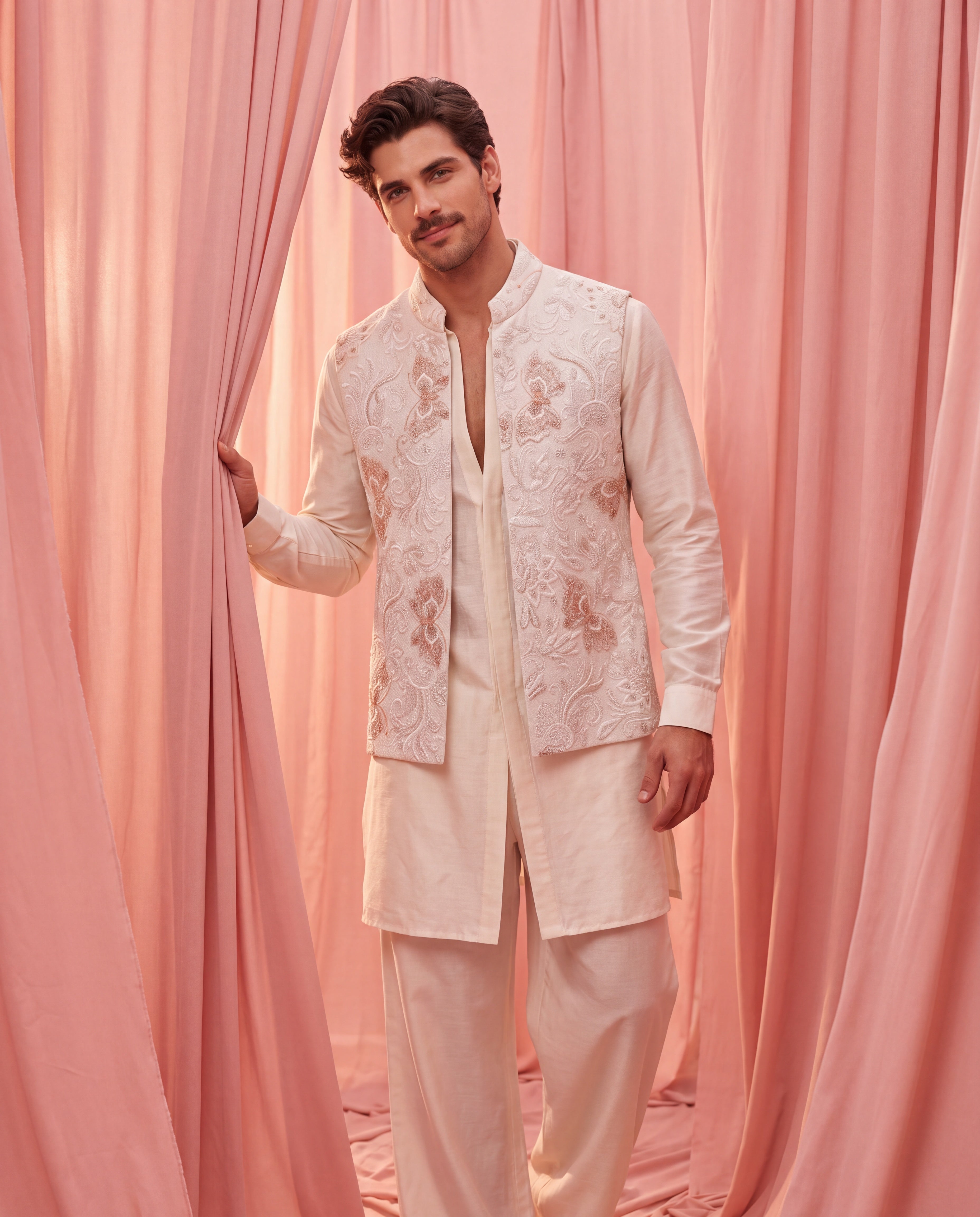 Cream herringbone waistcoat with hand-embroidered cream and blush pink detailing, paired with a plain silk cream kurta and matching aligadhi pants.