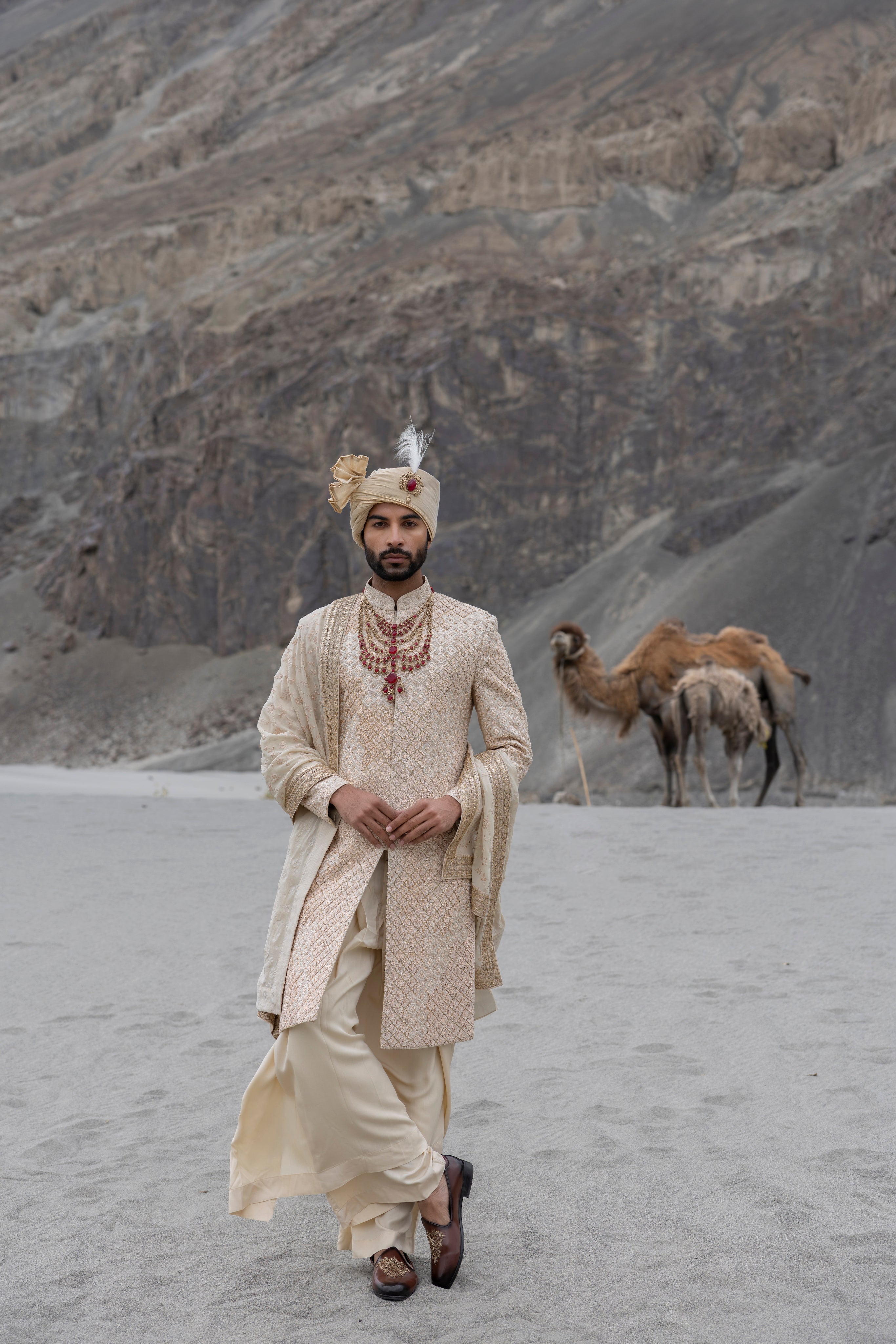 Beige raw silk sherwani with intricate hand-embroidery paired with a modal kurta pyjama & an embroidered geogrette stole.