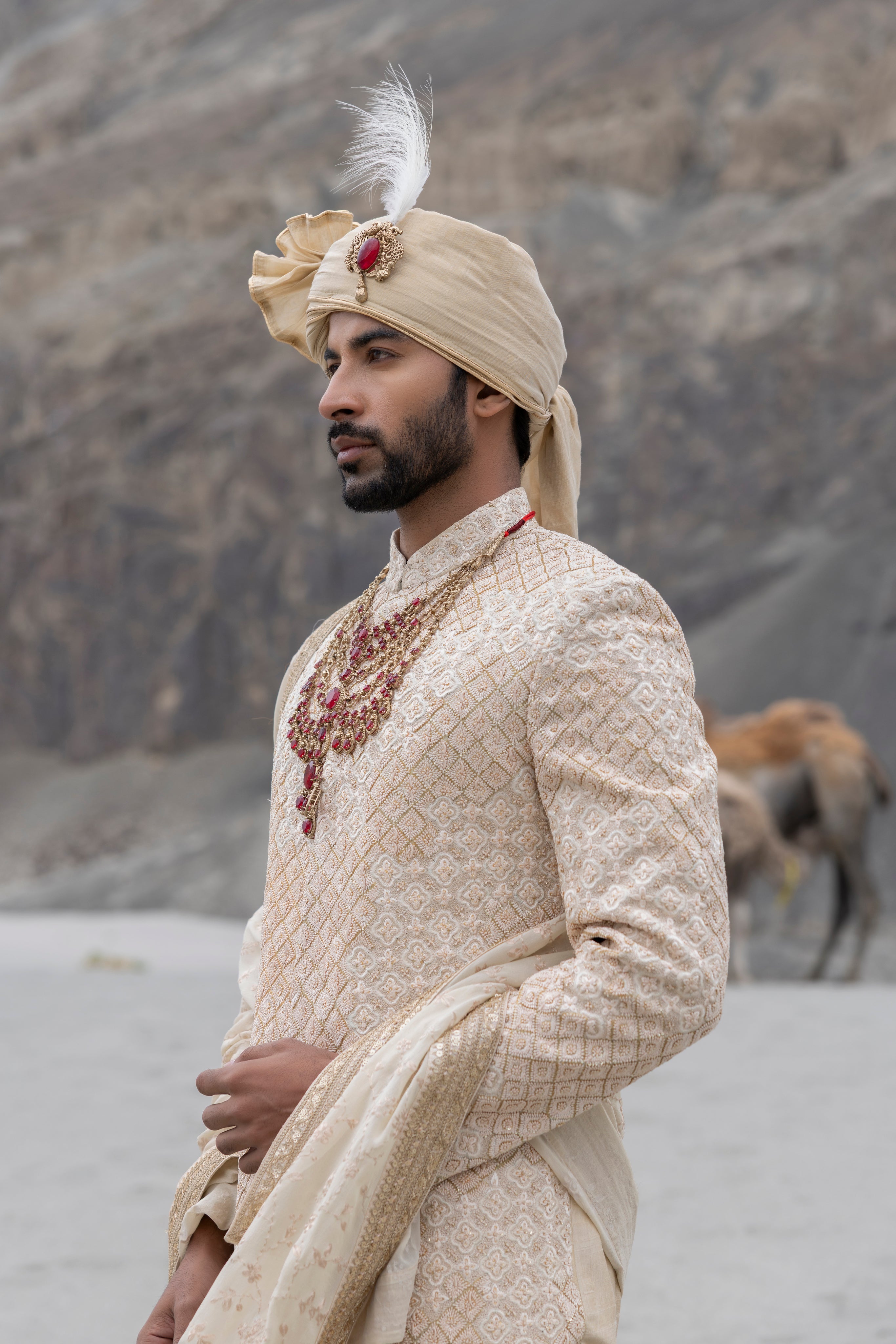 Beige raw silk sherwani with intricate hand-embroidery paired with a modal kurta pyjama & an embroidered geogrette stole.