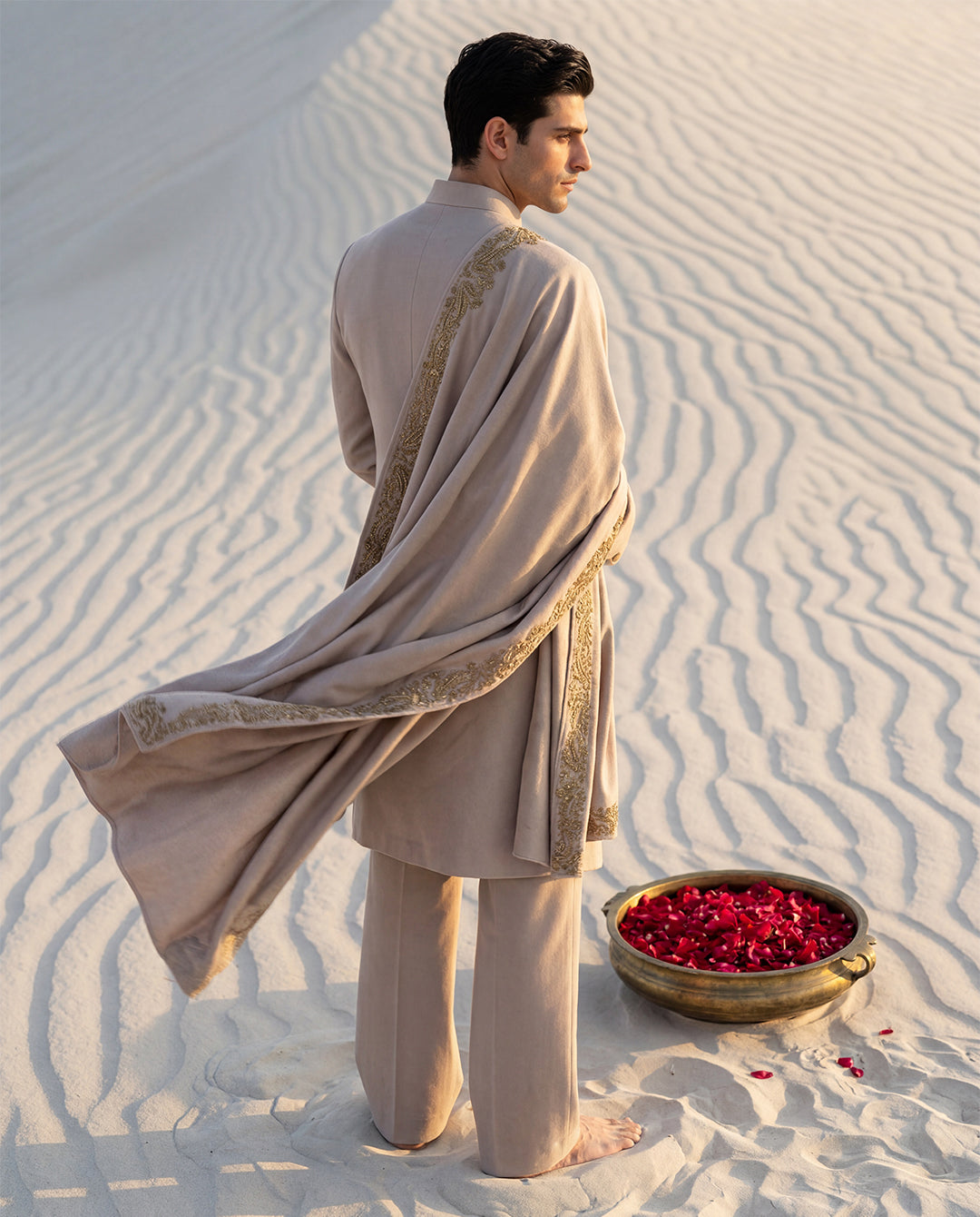 Beige Pashmina sherwani featuring gold buttons along the front, paired with matching pashmina pants and a pashmina stole embellished with a hand-embroidered border.