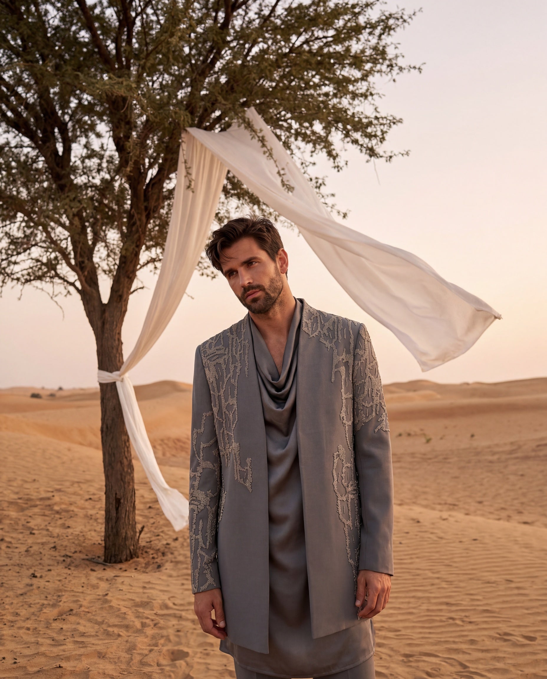 Grey knit Indo-Western jacket with metallic embroidery, paired with a cowl kurta and matching palazzo.