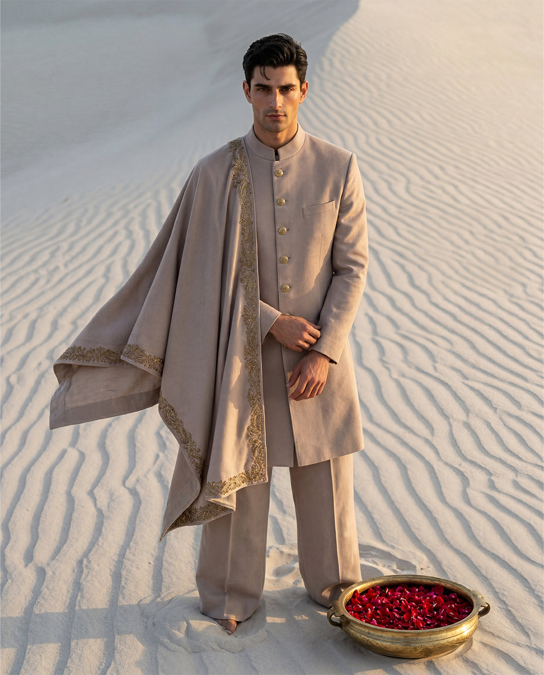 Beige Pashmina sherwani featuring gold buttons along the front, paired with matching pashmina pants and a pashmina stole embellished with a hand-embroidered border.
