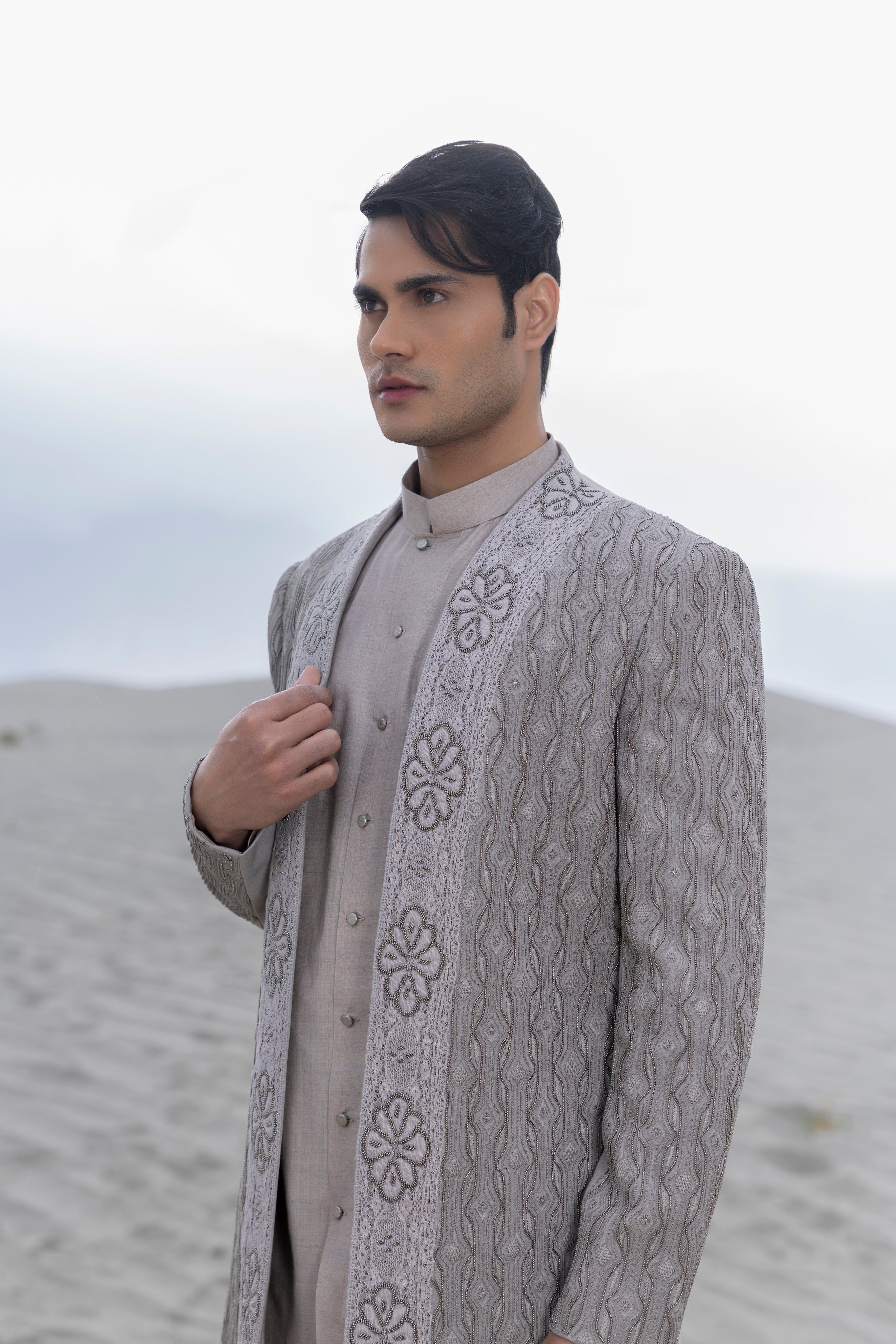 Grey front open indowestern jacket with crochet and metal hand-embroidery paired with a button down kurta and pants.