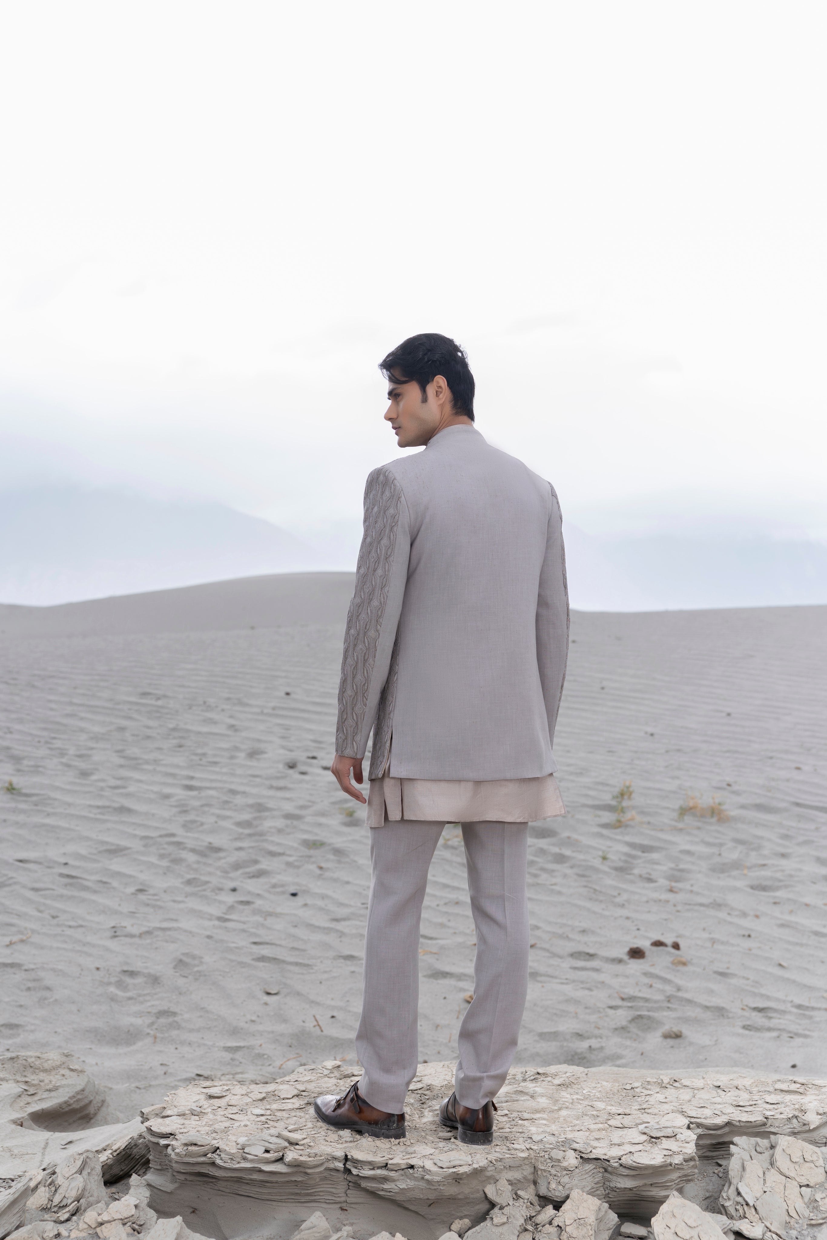 Grey front open indowestern jacket with crochet and metal hand-embroidery paired with a button down kurta and pants.