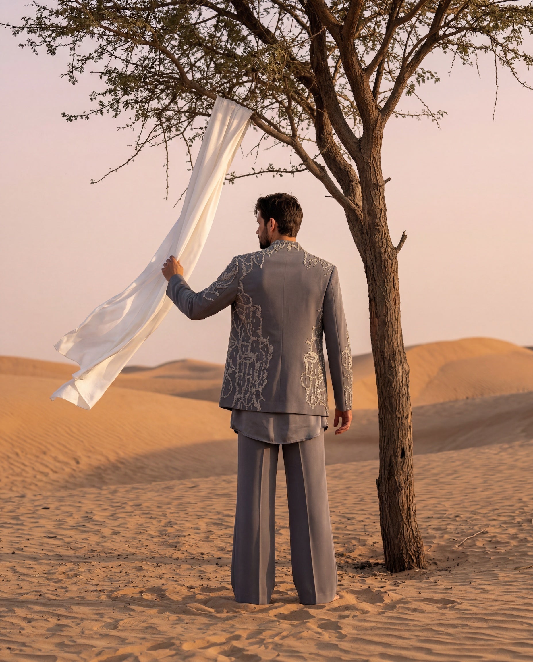 Grey knit Indo-Western jacket with metallic embroidery, paired with a cowl kurta and matching palazzo.