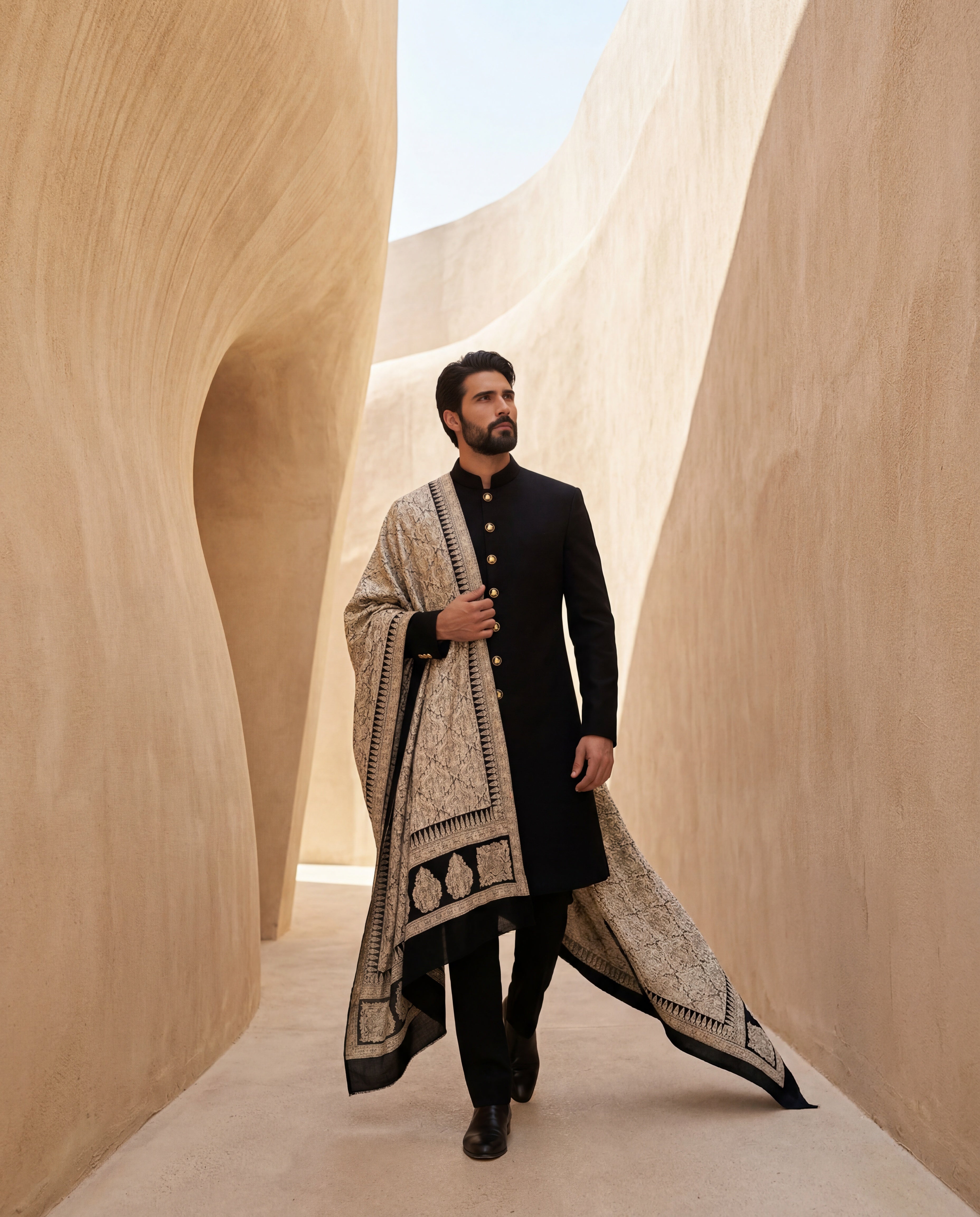 Black Pashmina sherwani featuring contrast buttons along the front, paired with matching pashmina pants and a pashmina stole with intricate gold toned Kashmiri hand-embroidery all over.