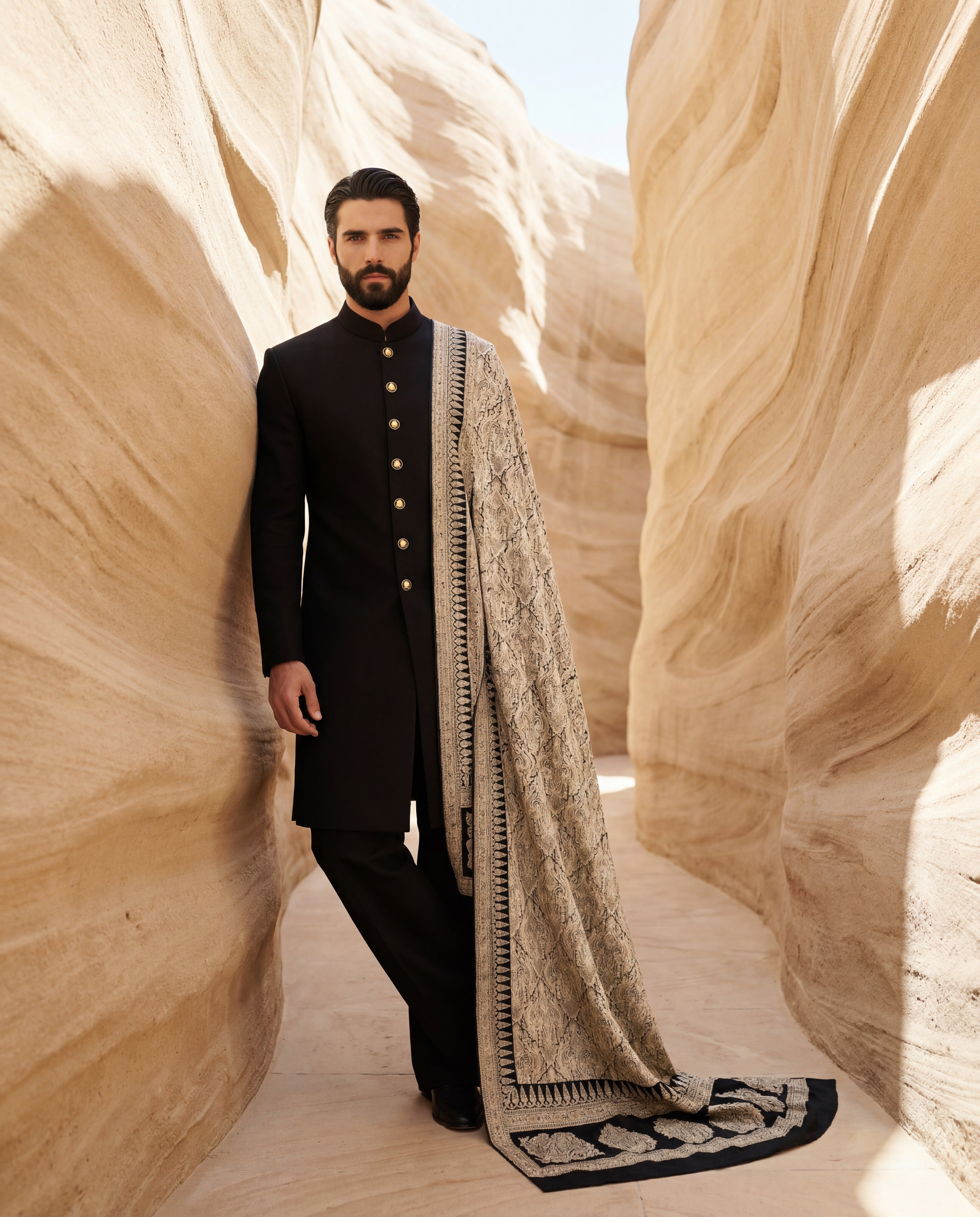 Black Pashmina sherwani featuring contrast buttons along the front, paired with matching pashmina pants and a pashmina stole with intricate gold toned Kashmiri hand-embroidery all over.