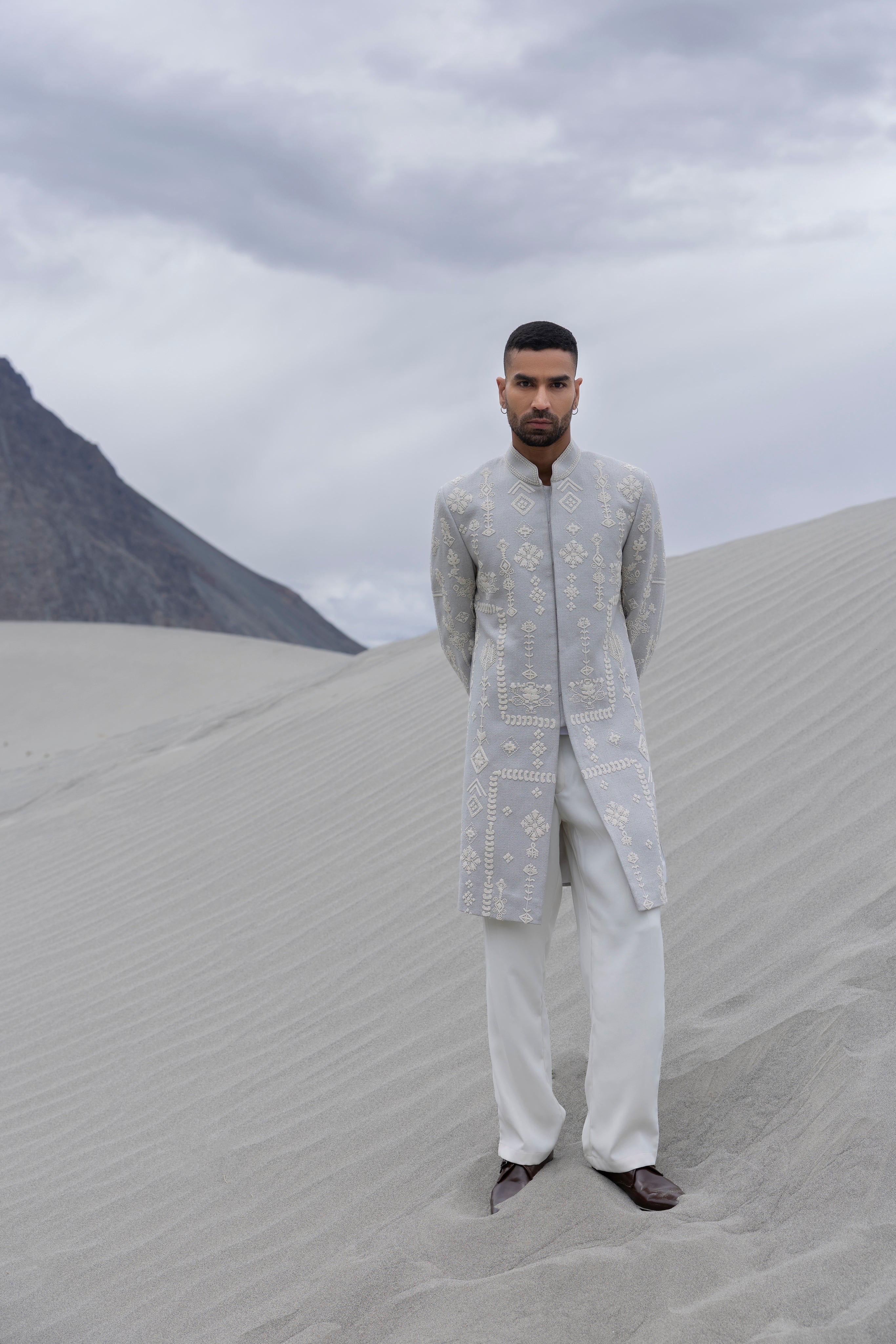 Grey long indowestern jacket with ivory hand-embroidered motifs paired with an ivory pant.