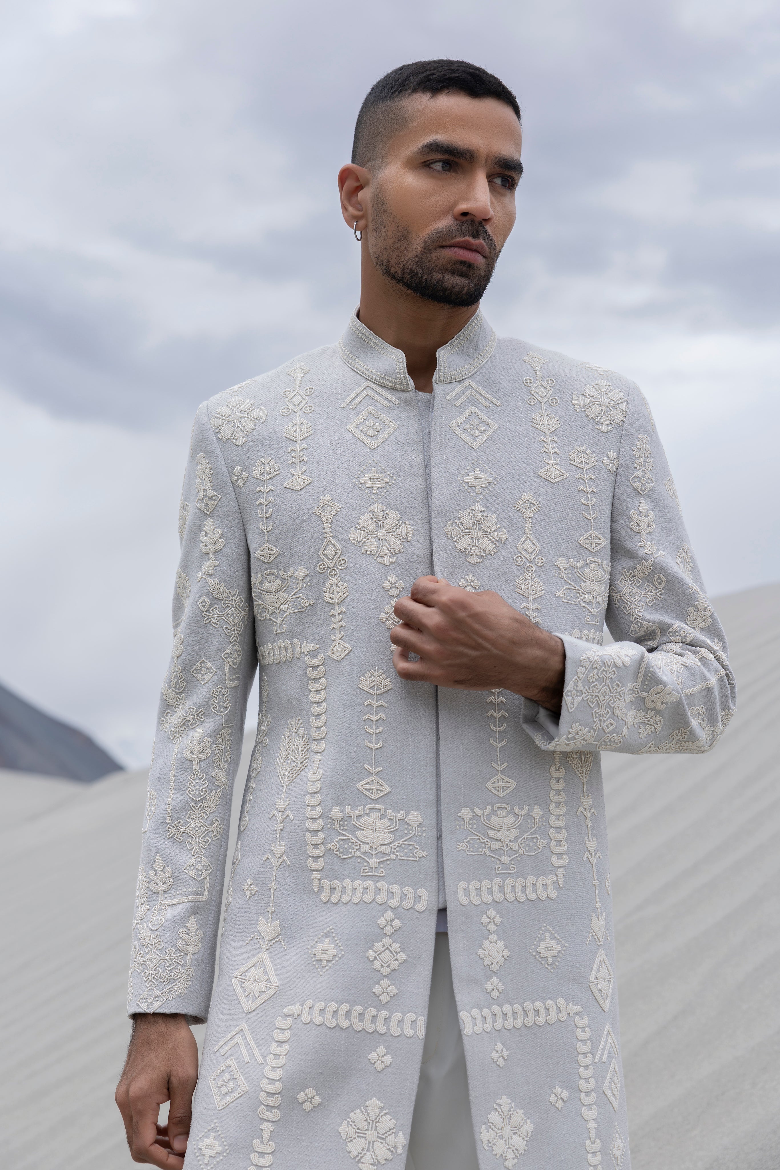 Grey long indowestern jacket with ivory hand-embroidered motifs paired with an ivory pant.