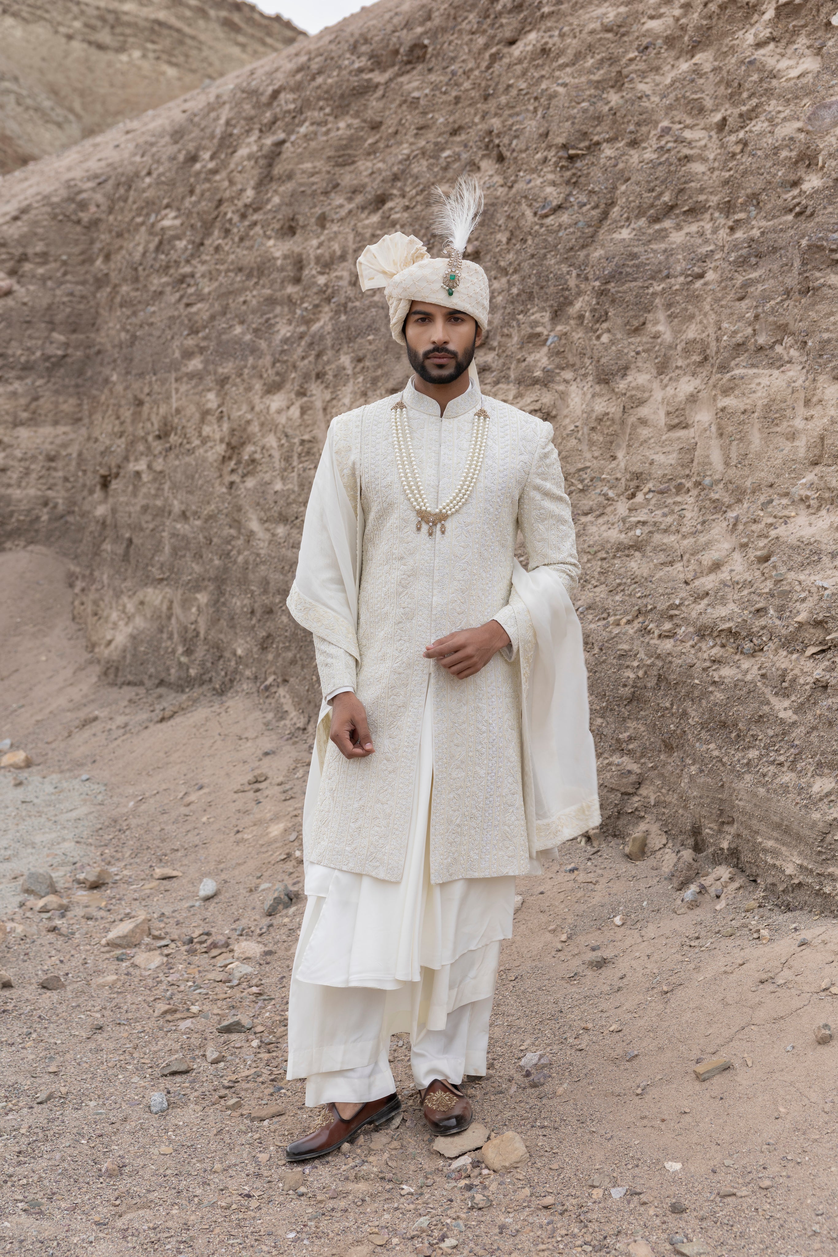 Cream textured poly knit sherwani with intricate hand-embroidery paired with a modal kurta pyjama & an organza stole.