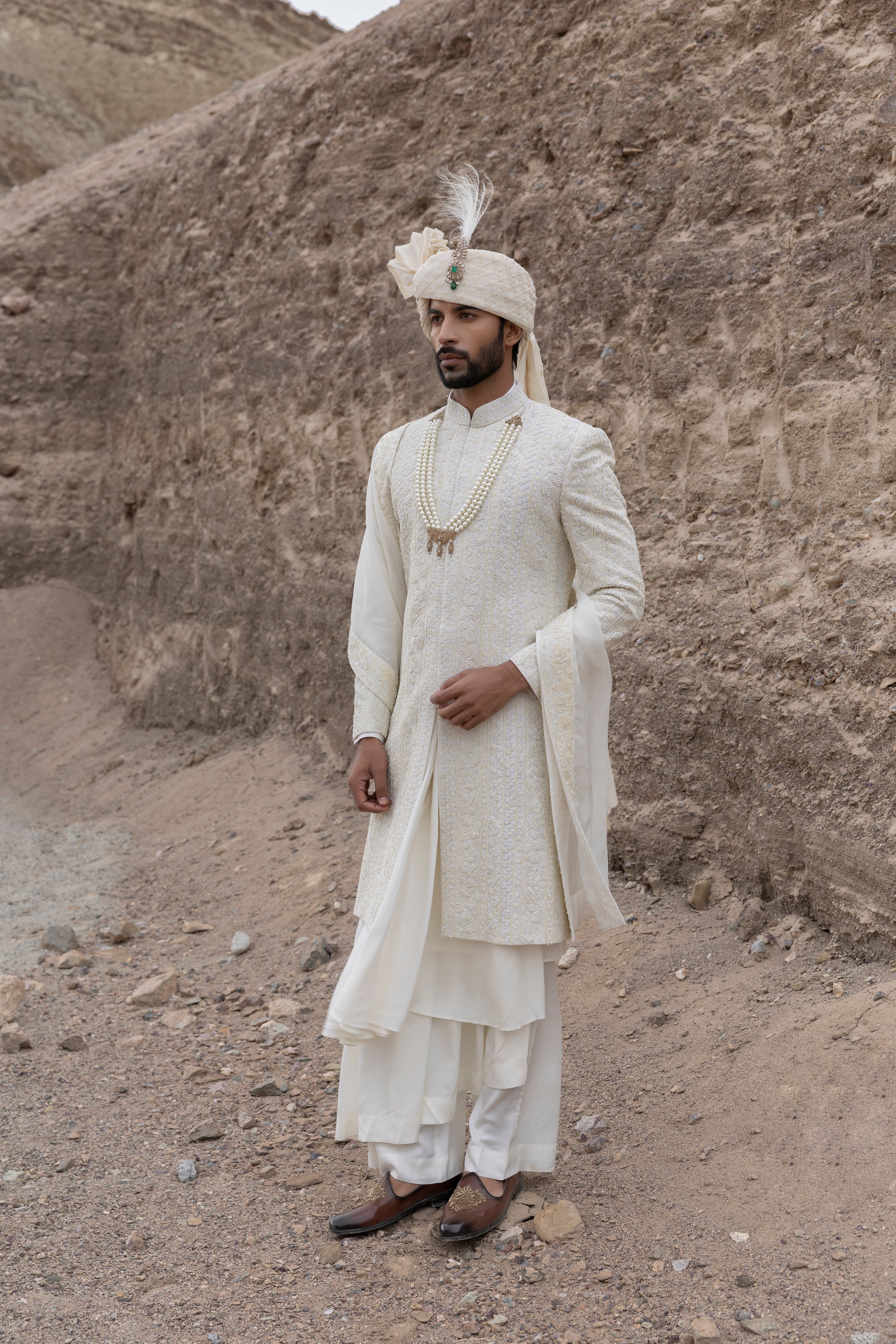 Cream textured poly knit sherwani with intricate hand-embroidery paired with a modal kurta pyjama & an organza stole.