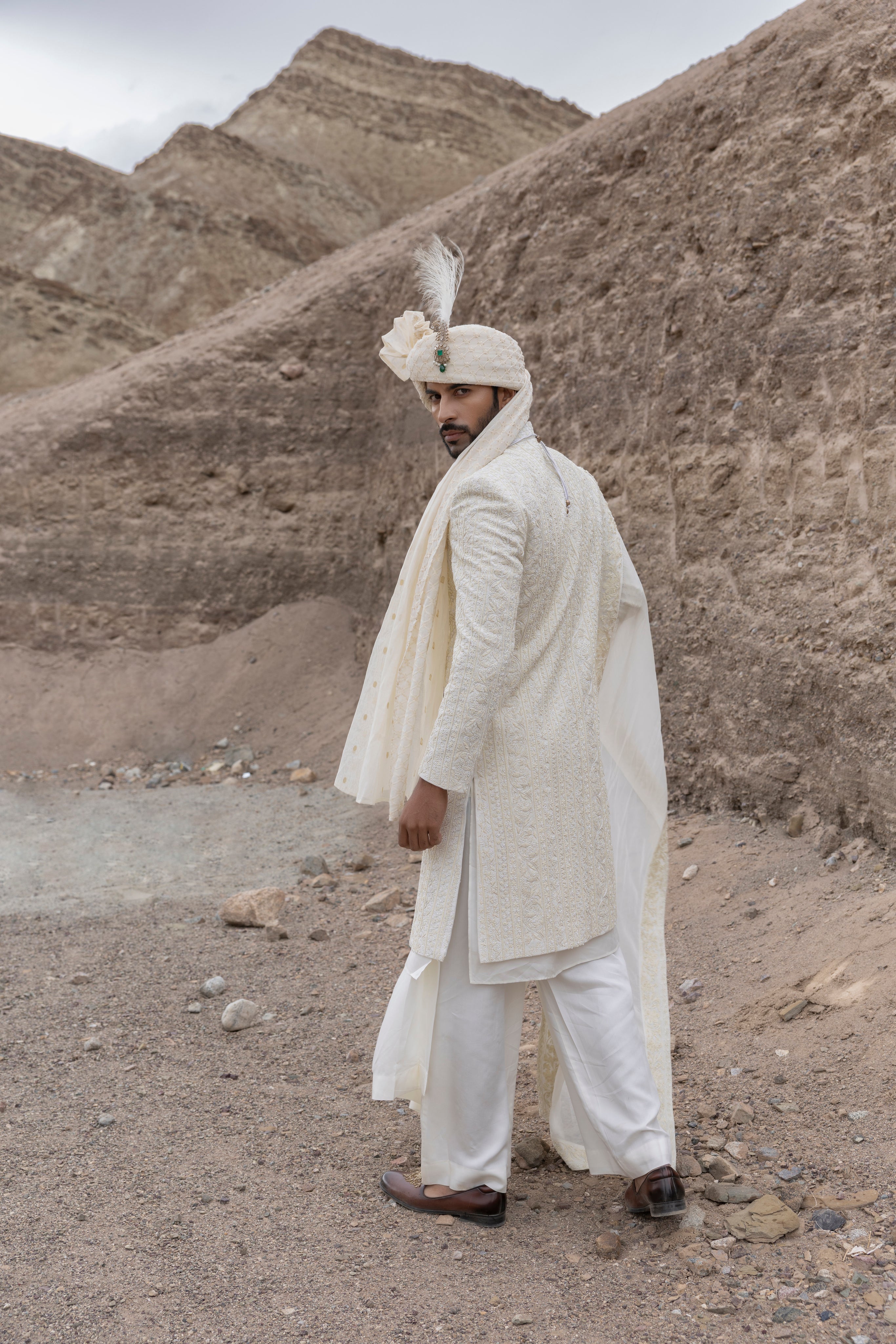 Cream textured poly knit sherwani with intricate hand-embroidery paired with a modal kurta pyjama & an organza stole.