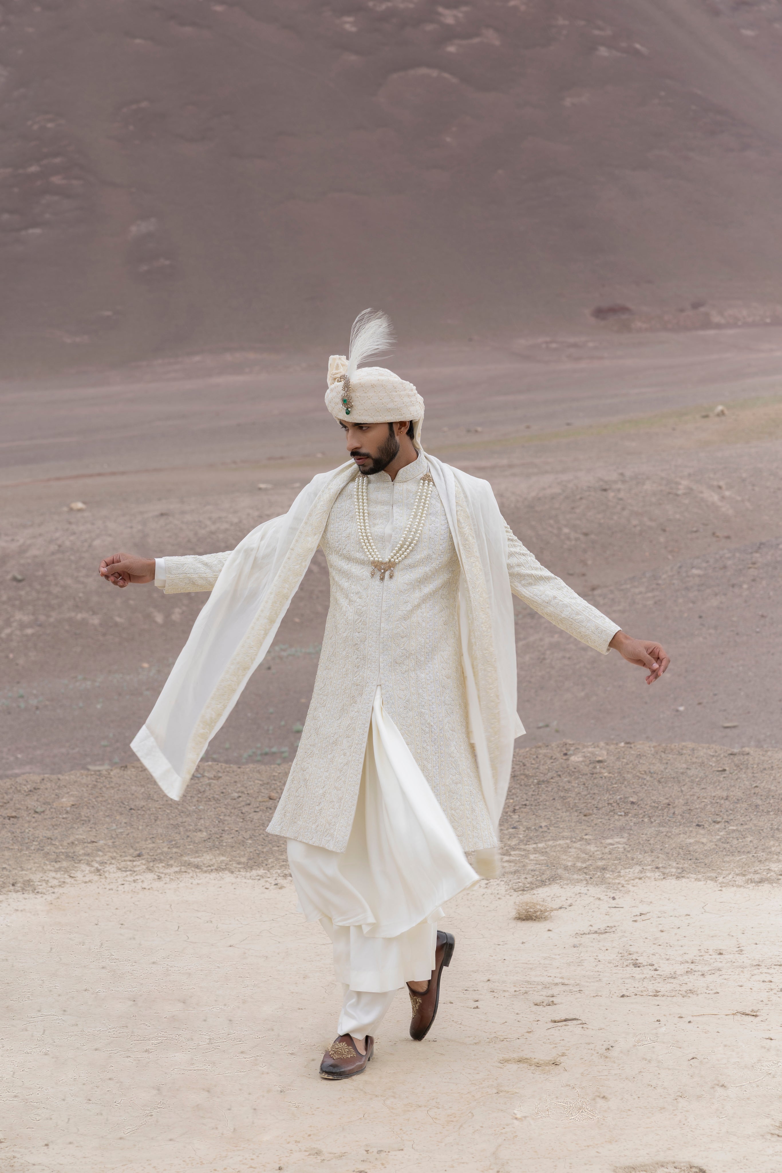 Cream textured poly knit sherwani with intricate hand-embroidery paired with a modal kurta pyjama & an organza stole.