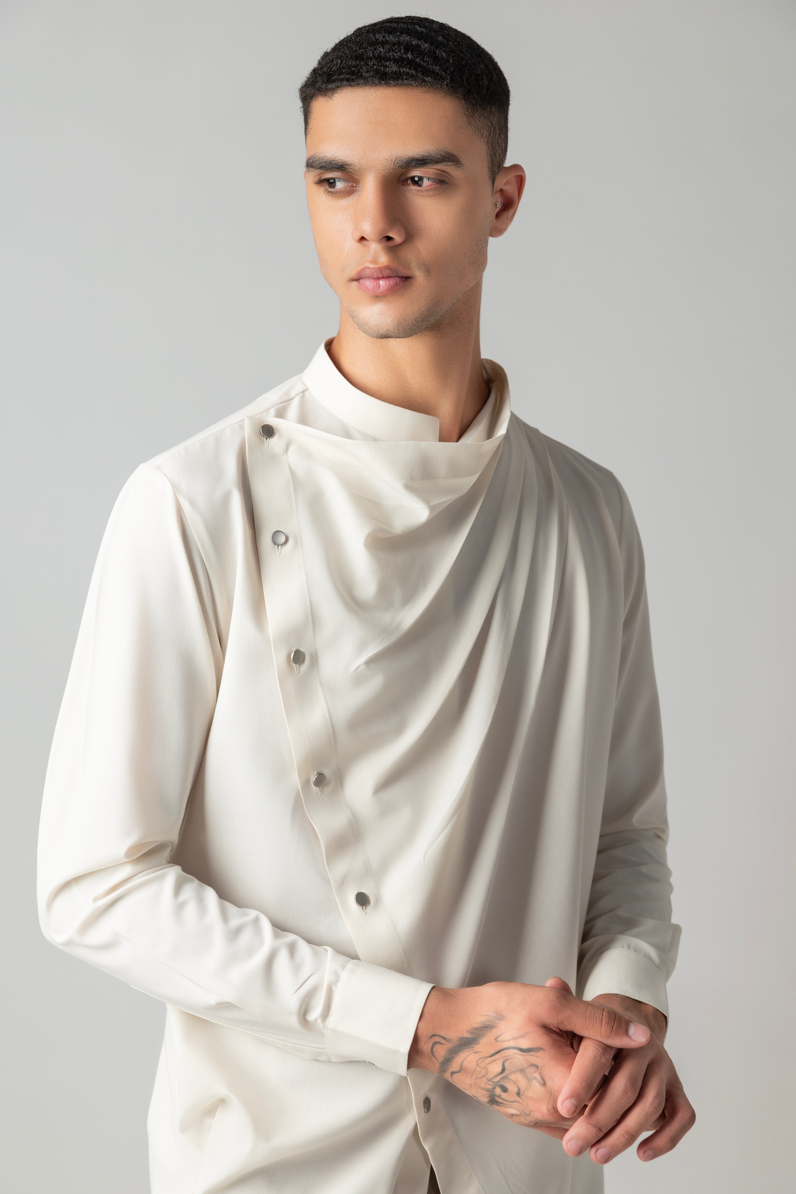 Cream shirt with asymmetrical buttons & drape detailing.