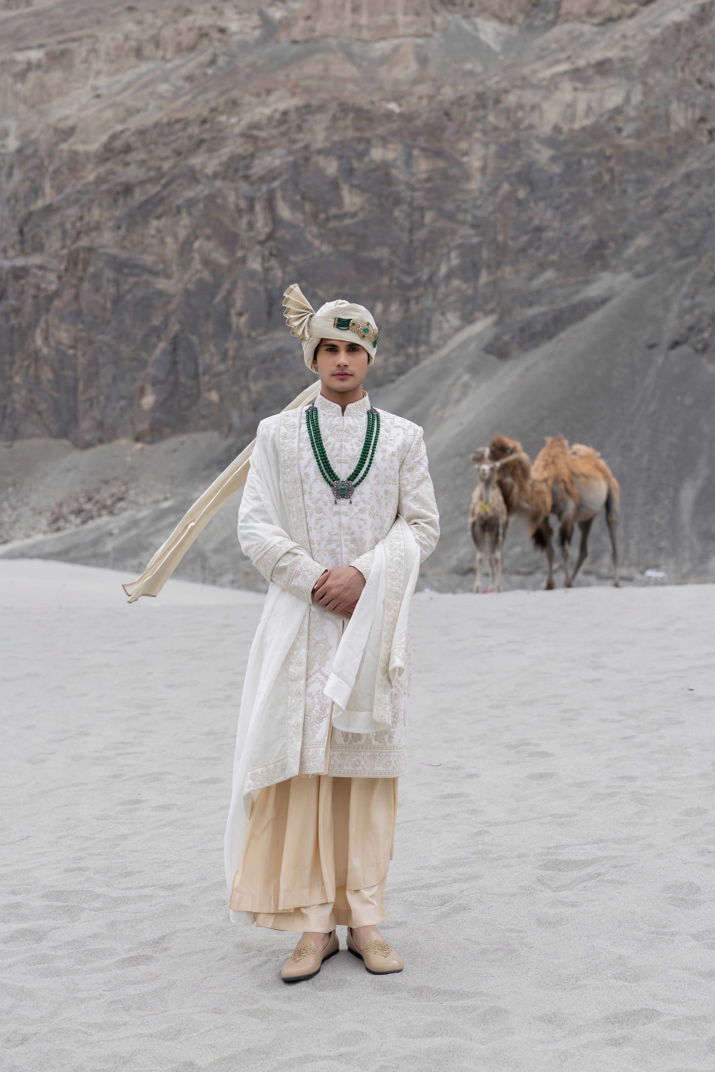 Cream raw silk sherwani with intricate hand-embroidery paired with a contrast coloured modal kurta pyjama & an organza stole.