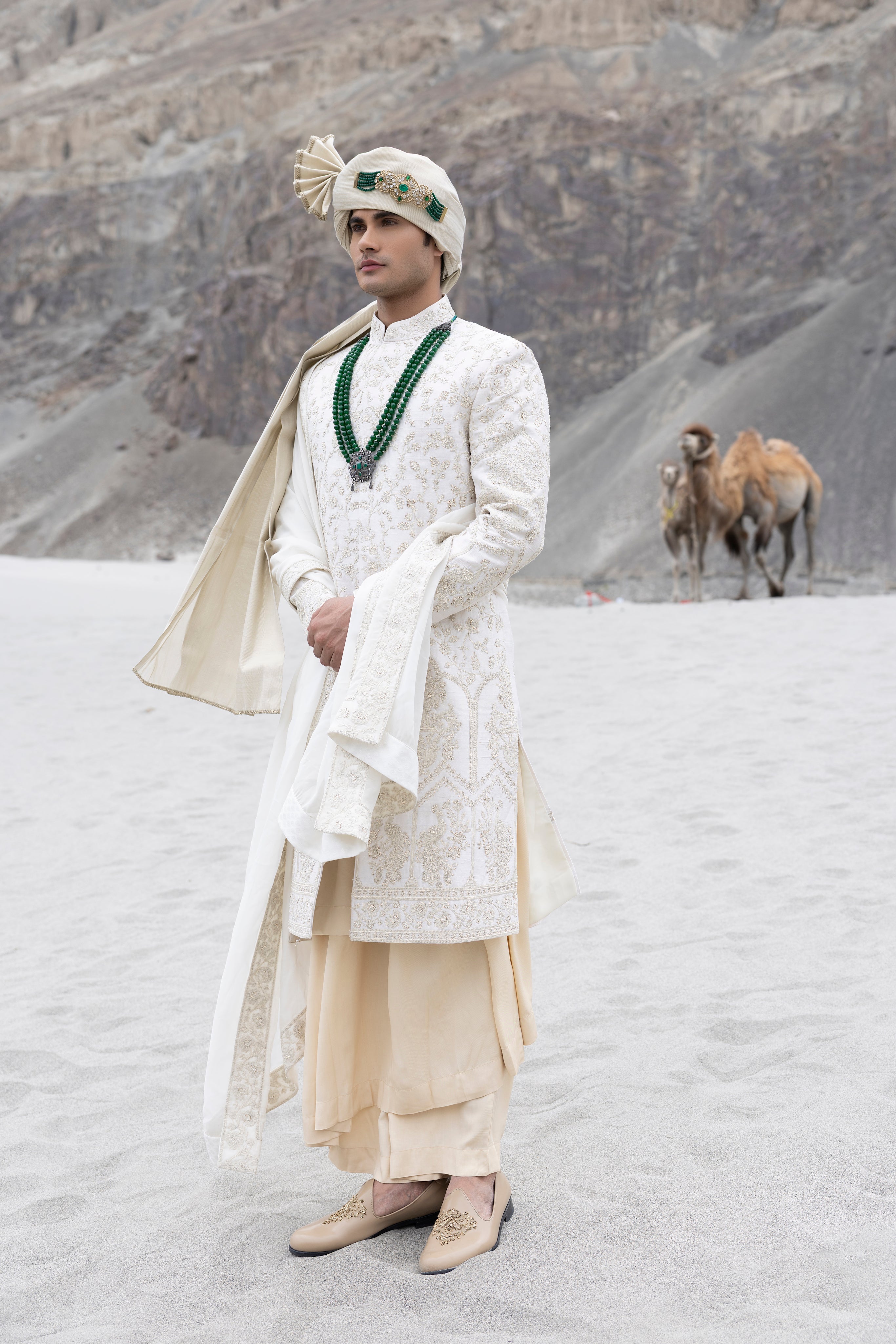 Cream raw silk sherwani with intricate hand-embroidery paired with a contrast coloured modal kurta pyjama & an organza stole.