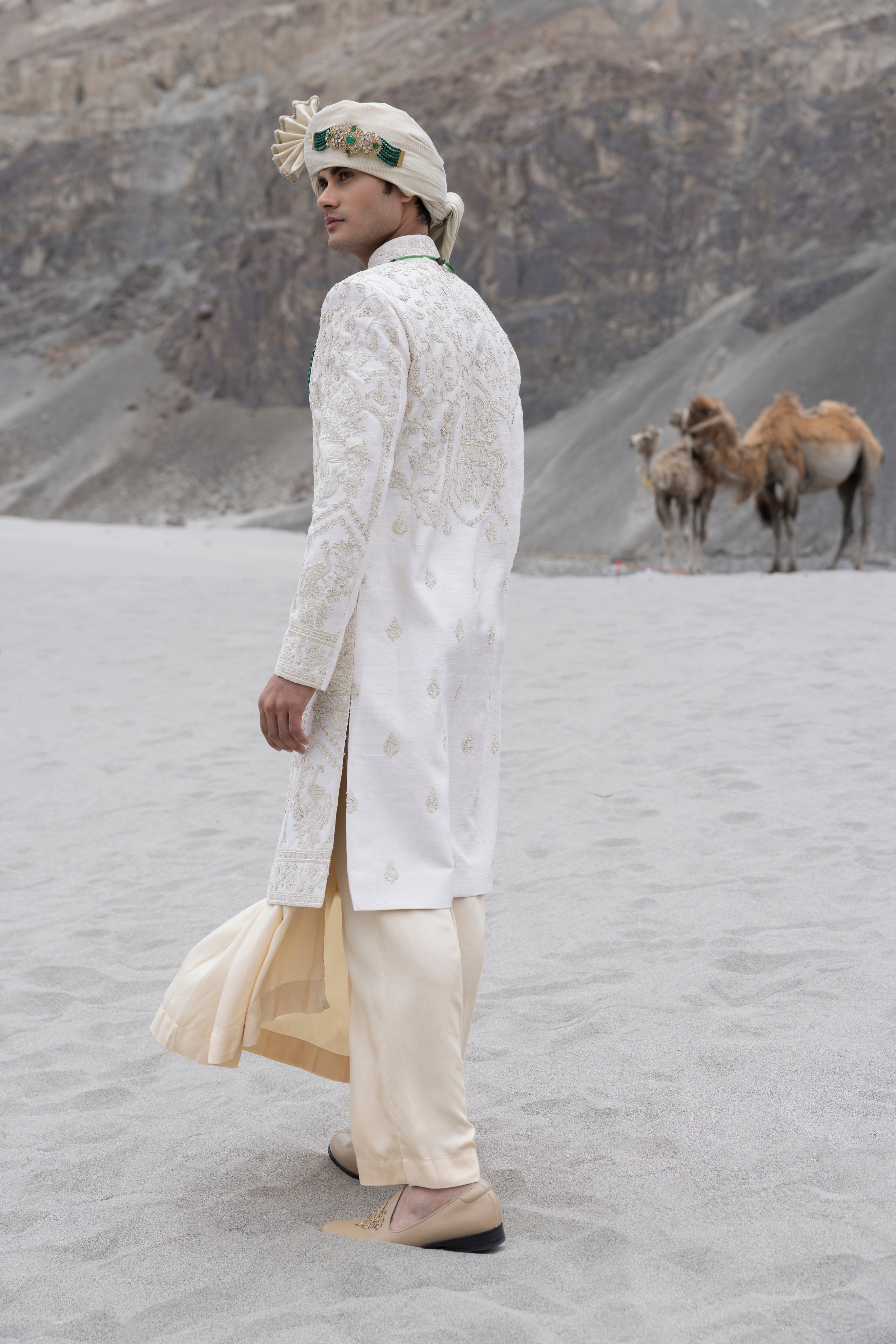 Cream raw silk sherwani with intricate hand-embroidery paired with a contrast coloured modal kurta pyjama & an organza stole.