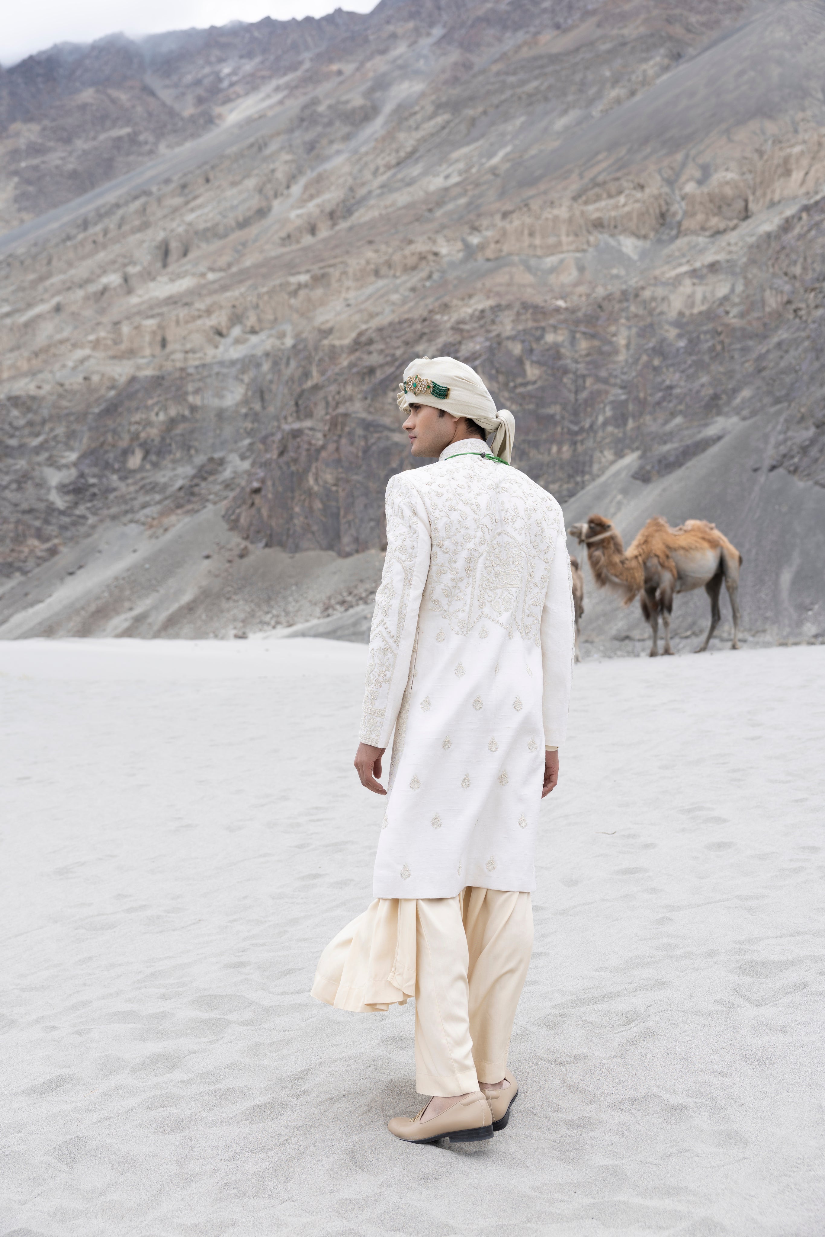 Cream raw silk sherwani with intricate hand-embroidery paired with a contrast coloured modal kurta pyjama & an organza stole.