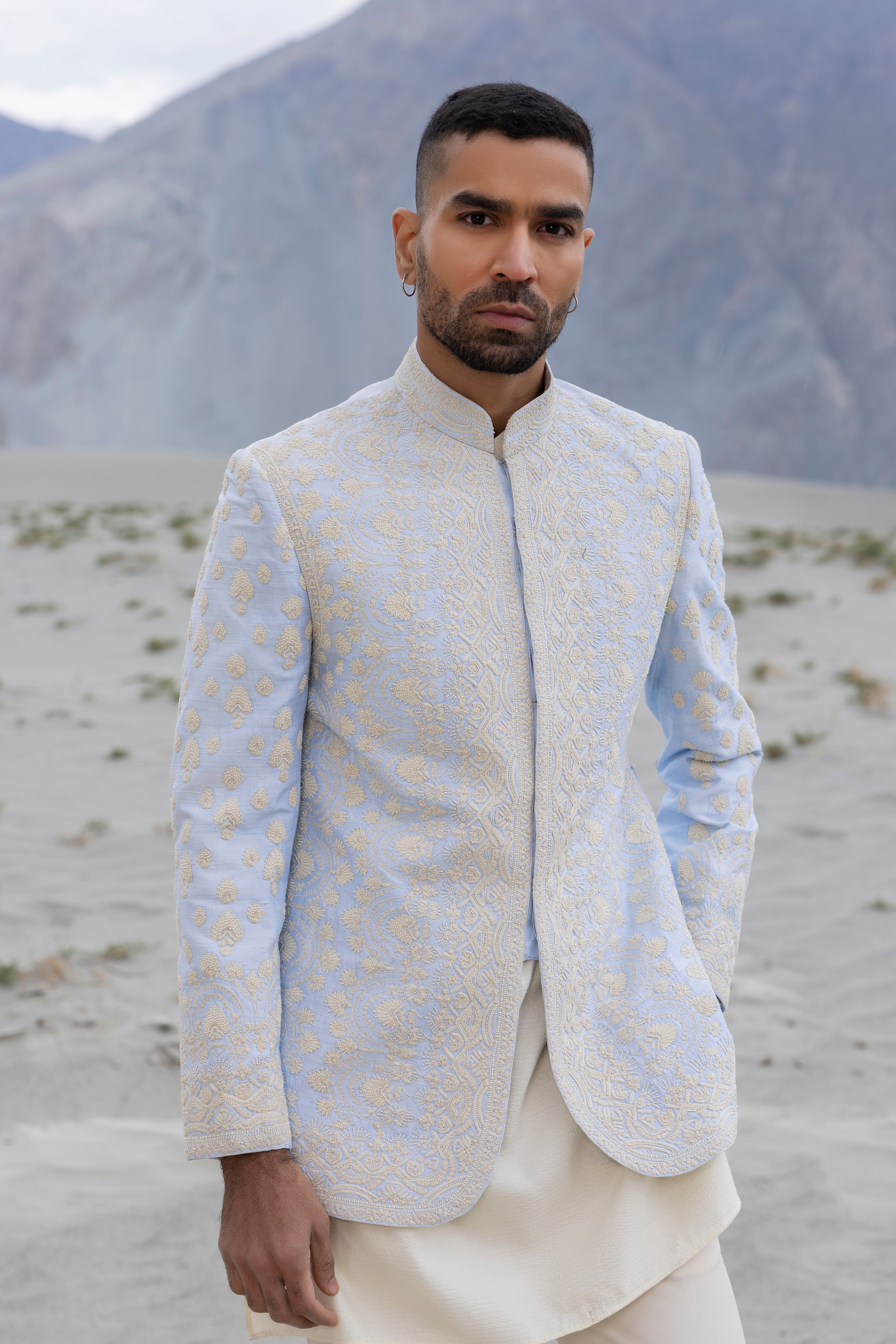 Sky Blue raw silk short indowestern jacket with icoty hand-embroidery paired with a jaquard silk kurta and a poly knit pant.