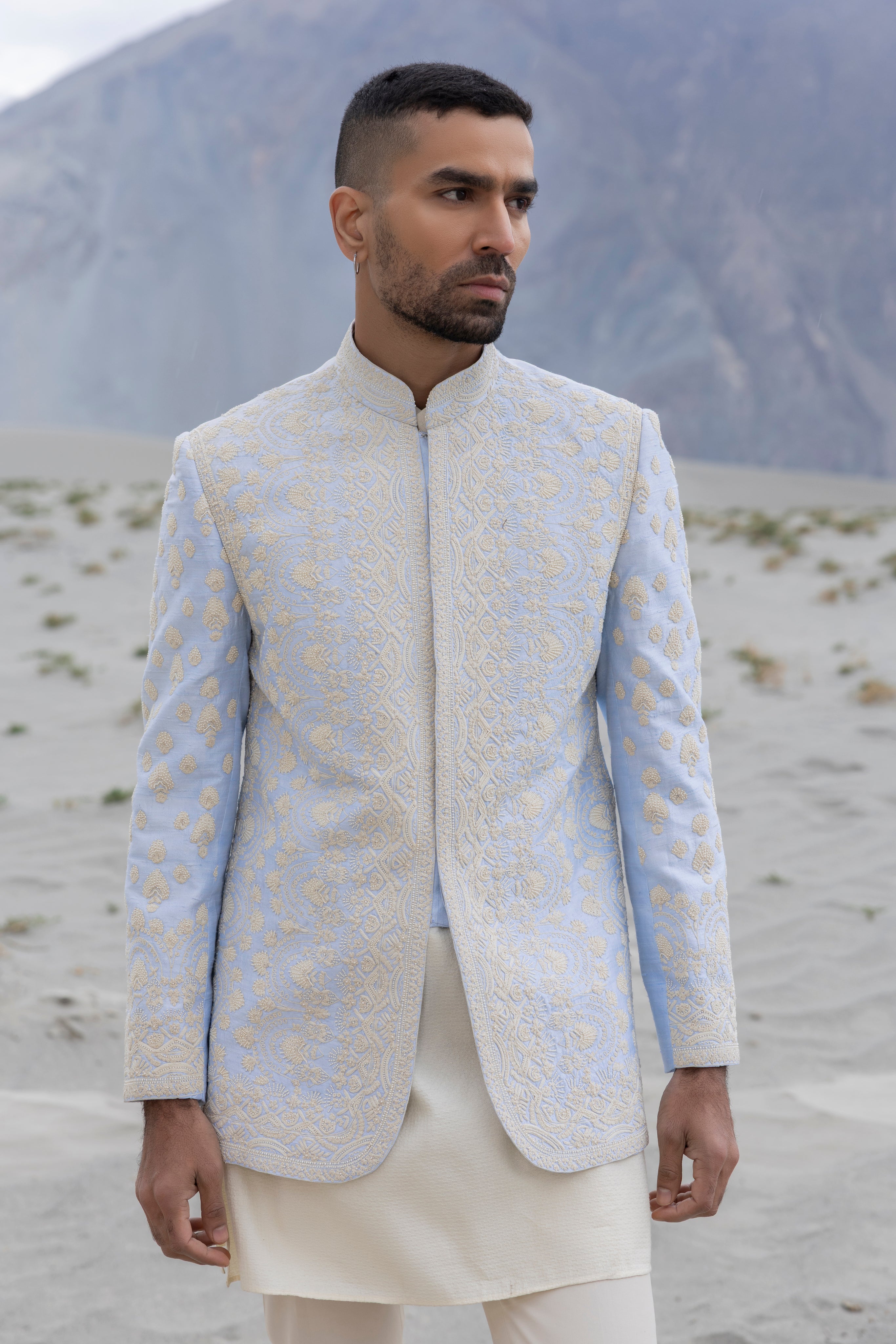 Sky Blue raw silk short indowestern jacket with icoty hand-embroidery paired with a jaquard silk kurta and a poly knit pant.