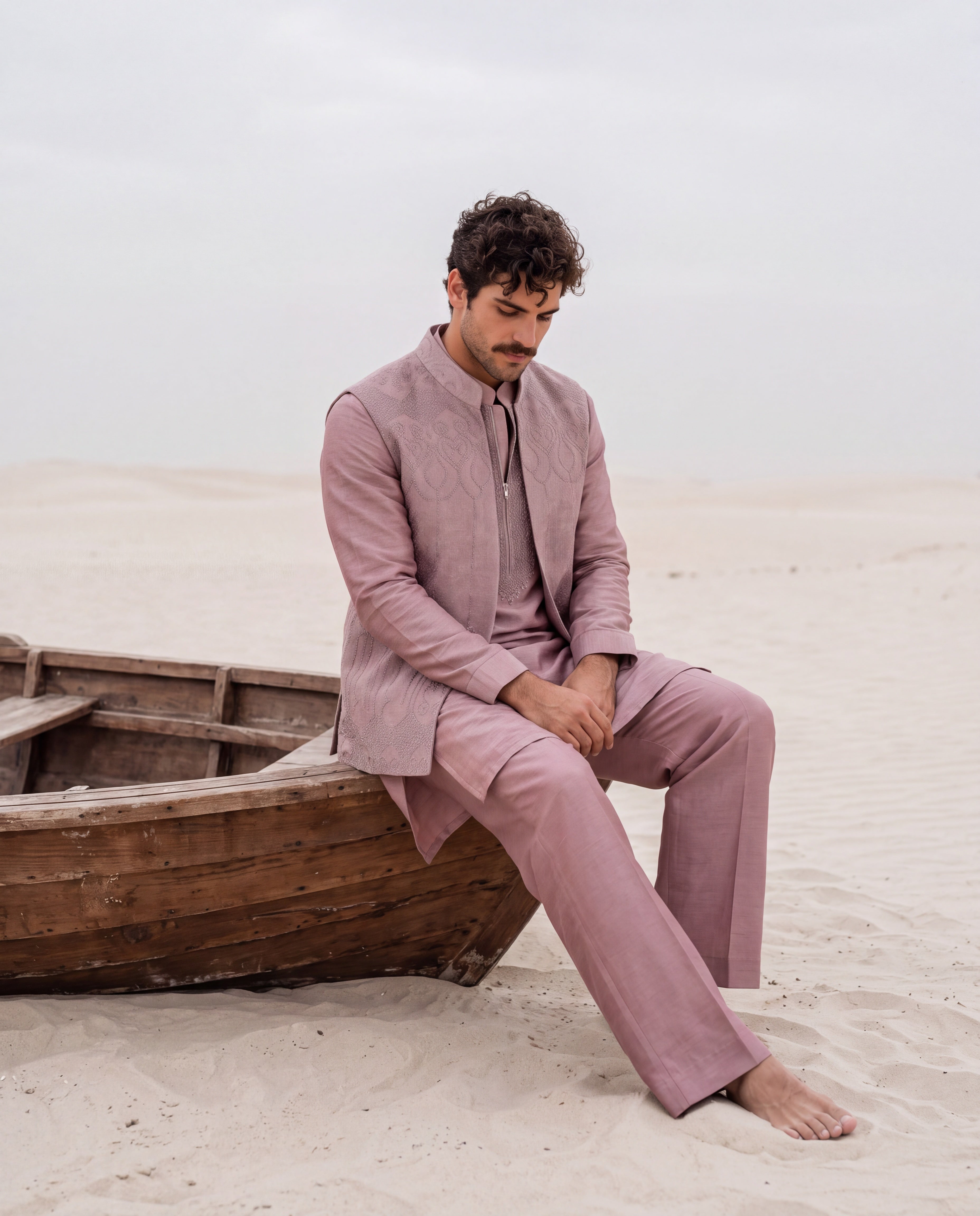 Mauve textured velevet waistcoat with monotone hand embroidery detailing, paired with an embroidered silk kurta and matching aligadhi pants.