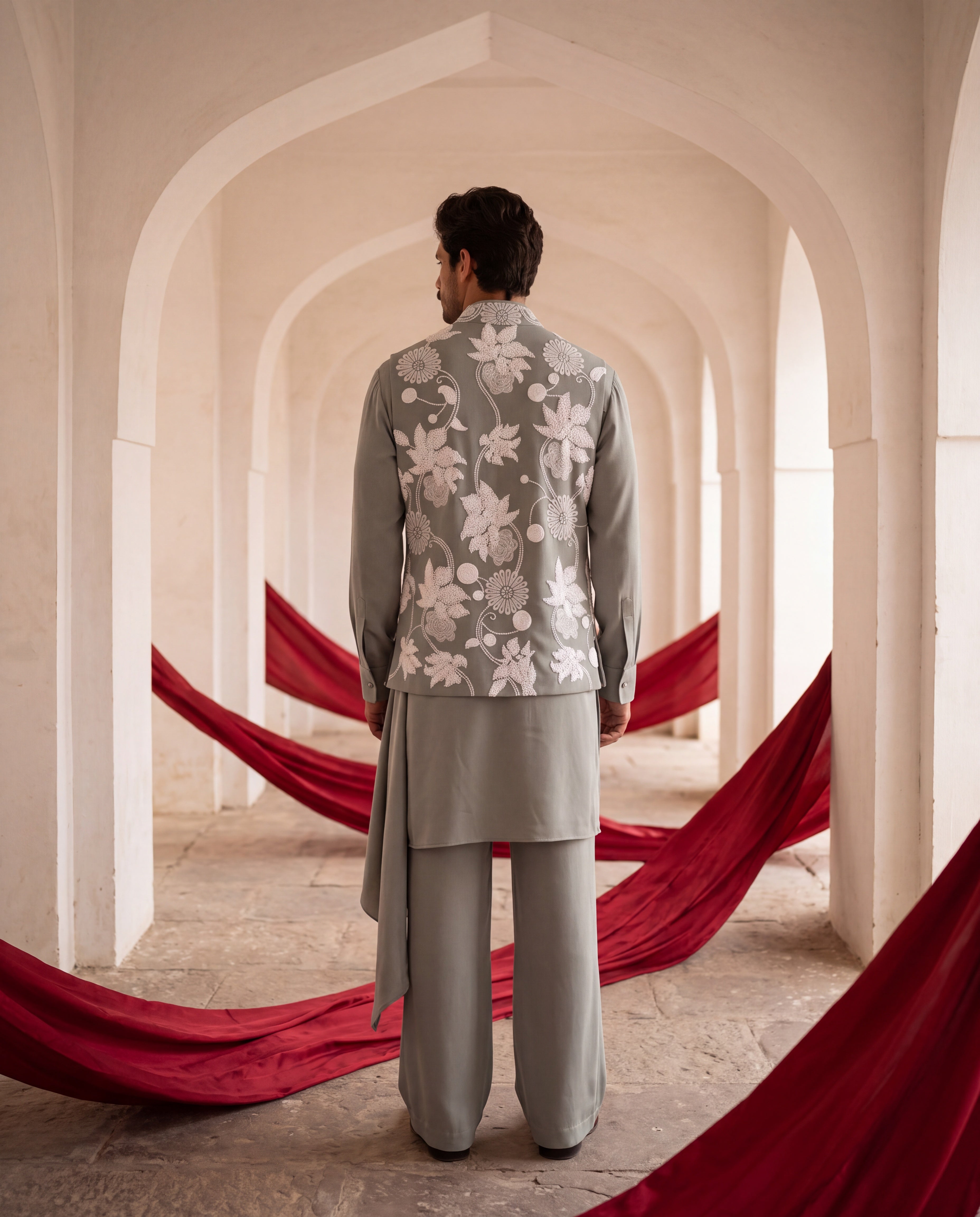 Pista green knit waistcoat with white floral hand-embroidery paired with a matching knit draped kurta and aligadhi pants.