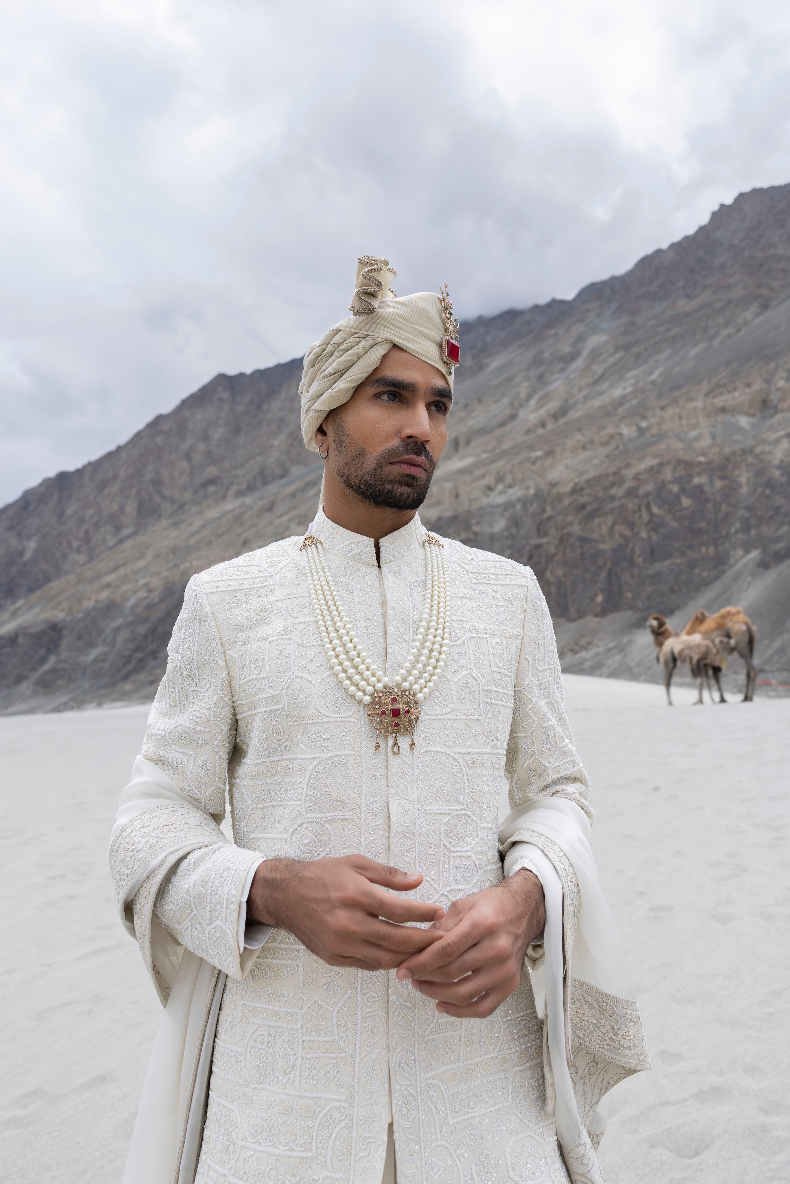 Cream raw silk sherwani with intricate hand-embroidery paired with a modal kurta pyjama & an organza stole.