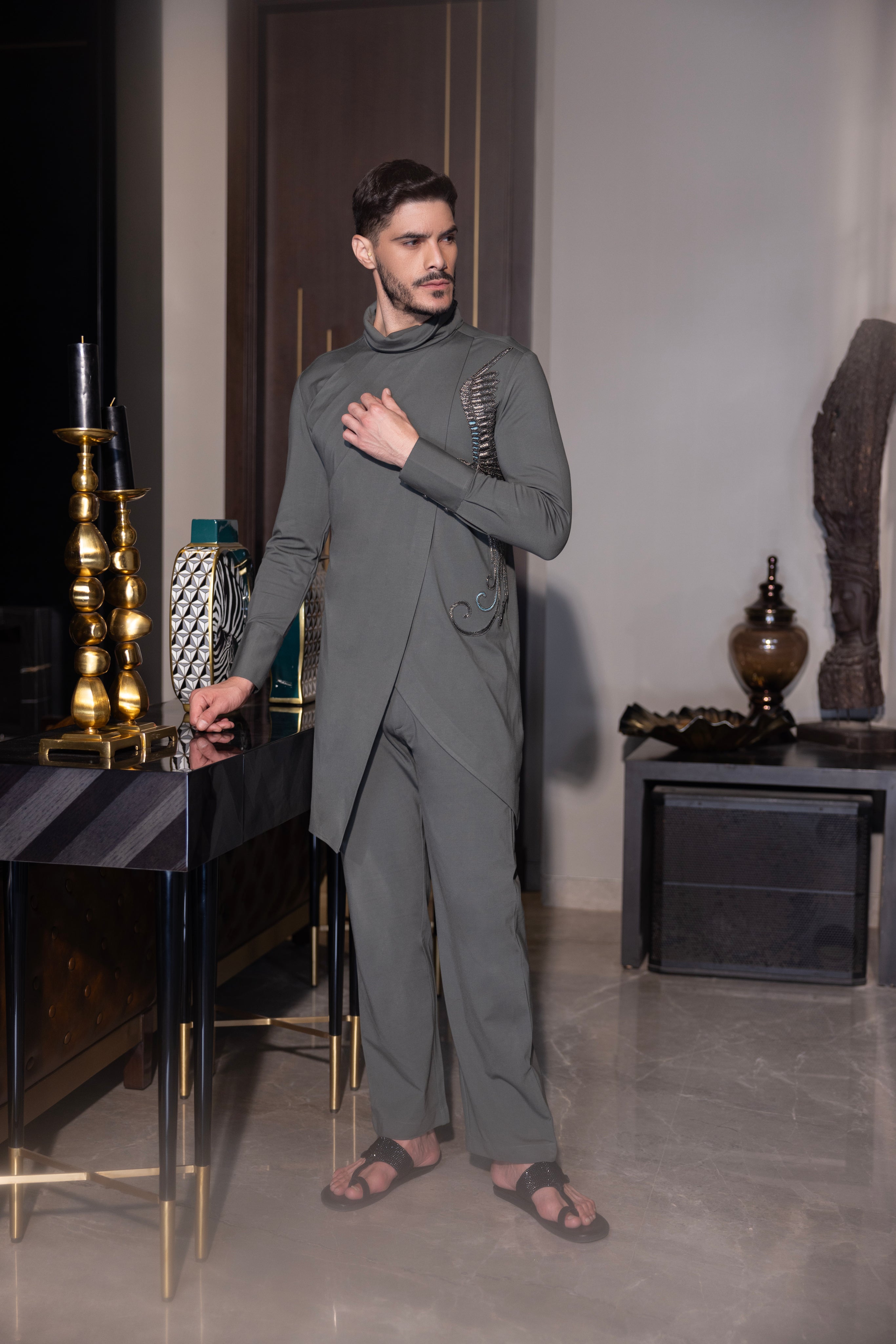 Olive green asymmetrical kurta with hand-embroidered bird motif  paired with a matching aligadhi set.