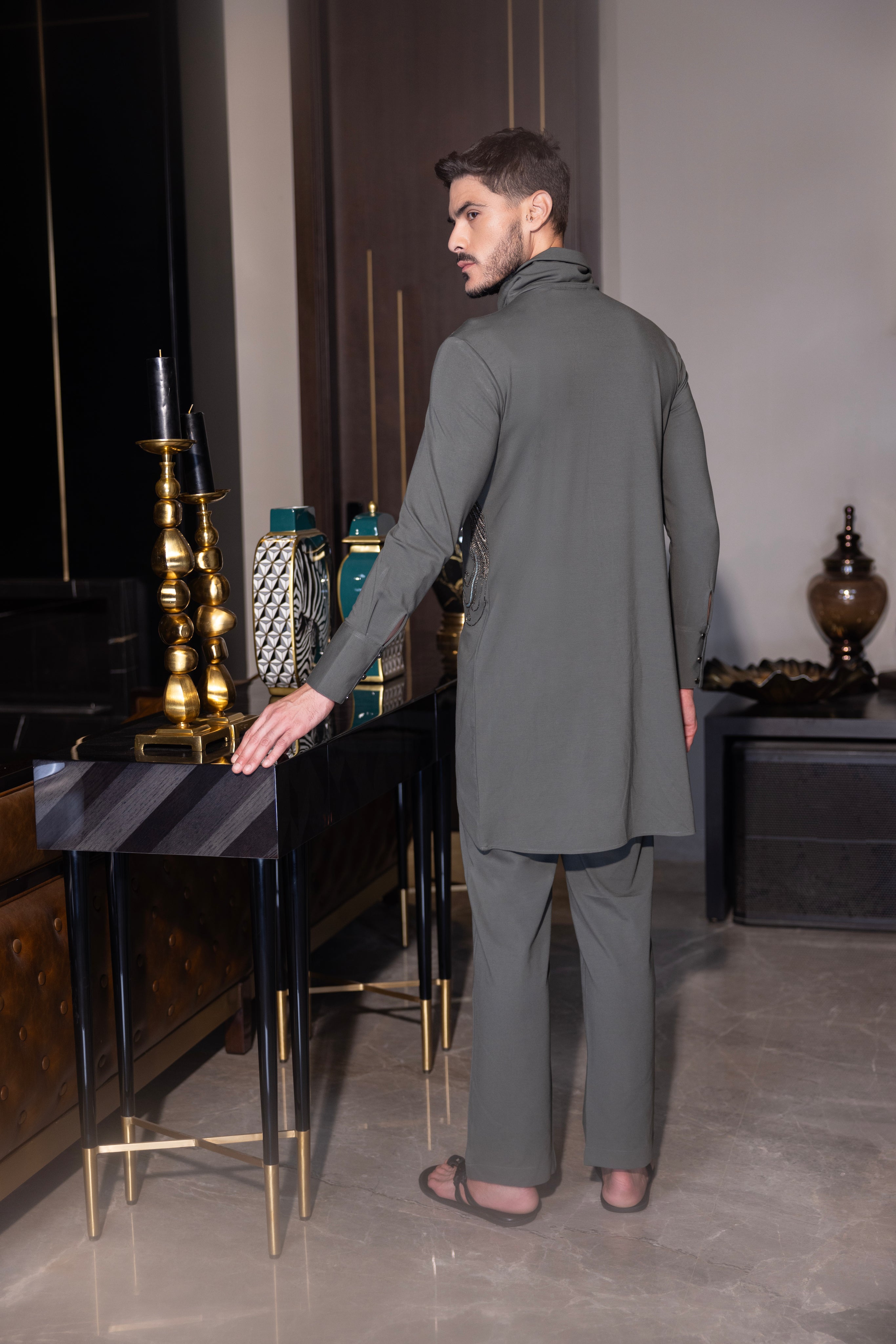 Olive green asymmetrical kurta with hand-embroidered bird motif  paired with a matching aligadhi set.