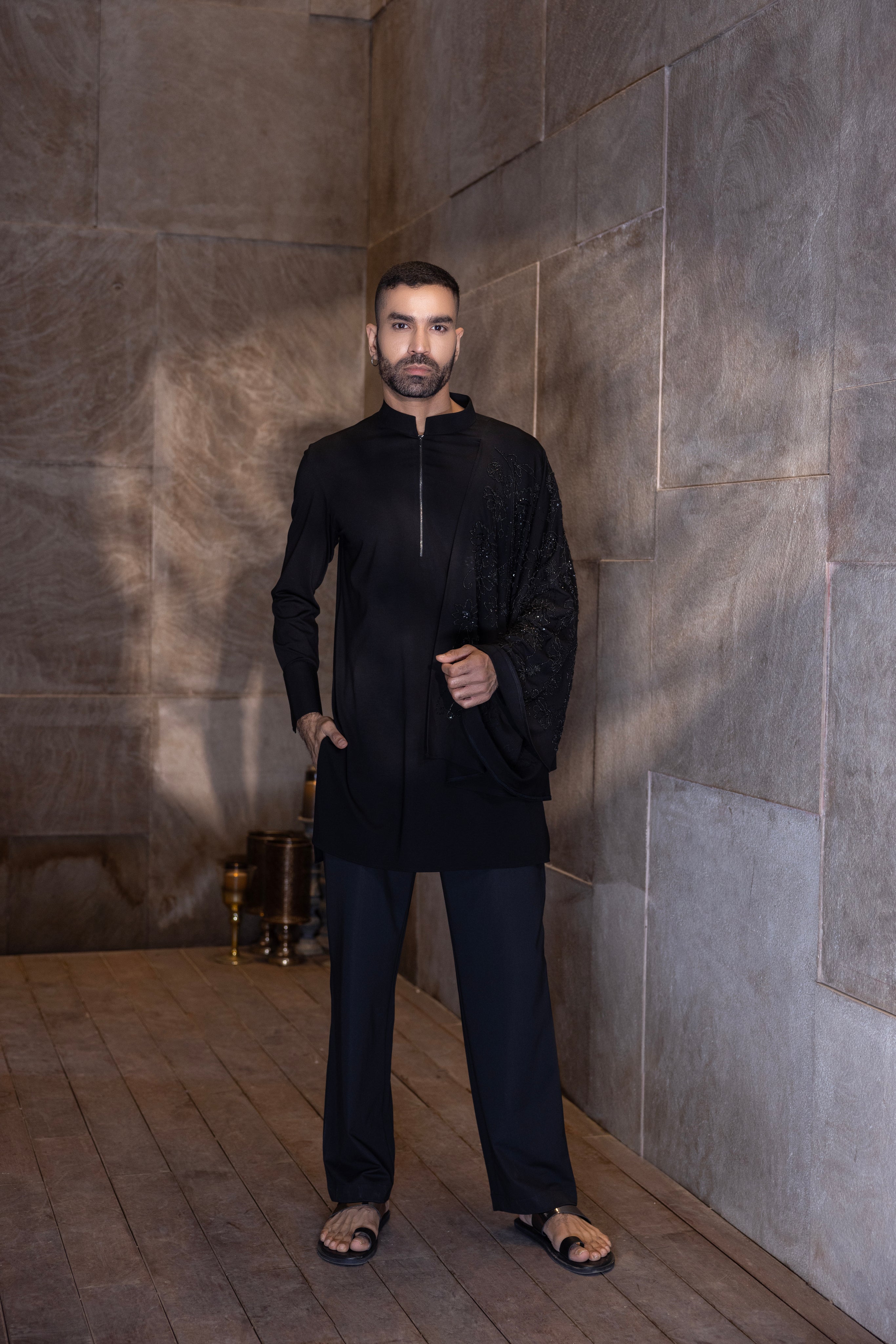 Black hand-embroidered kurta with draping details paired with a matching aligadhi set.