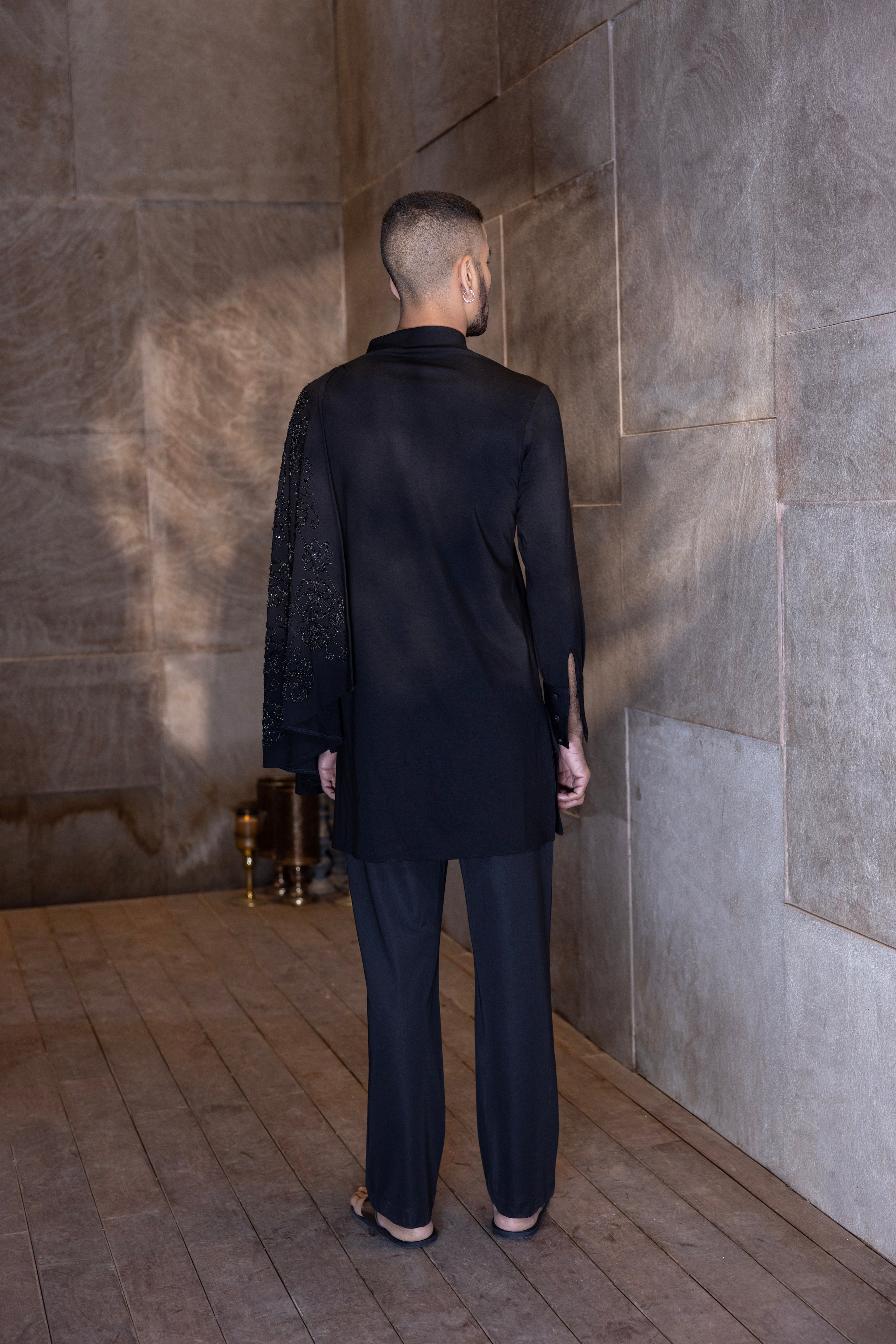 Black hand-embroidered kurta with draping details paired with a matching aligadhi set.