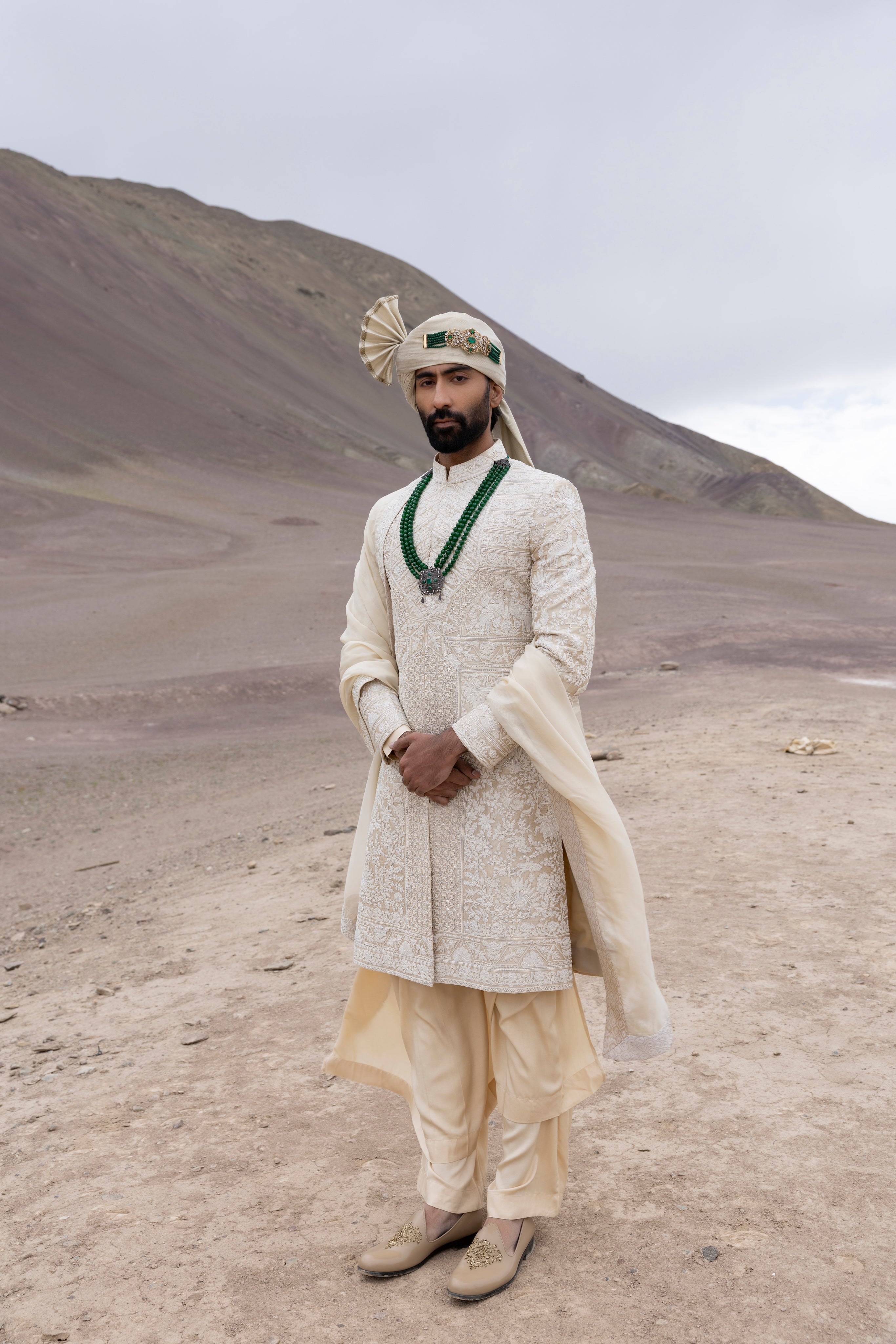 Beige raw silk sherwani with intricate hand-embroidery paired with a modal kurta pyjama & an organza stole.