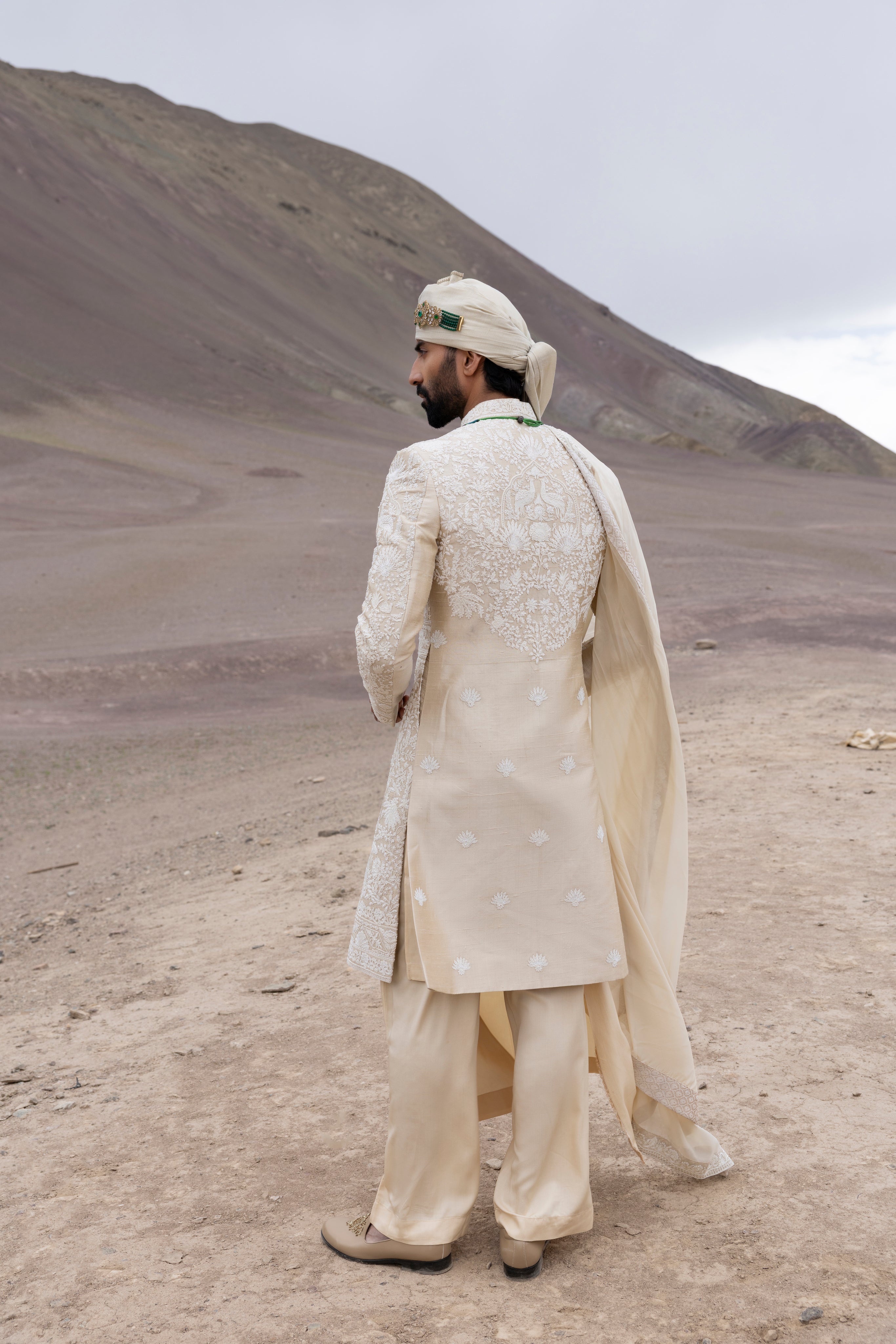 Beige raw silk sherwani with intricate hand-embroidery paired with a modal kurta pyjama & an organza stole.
