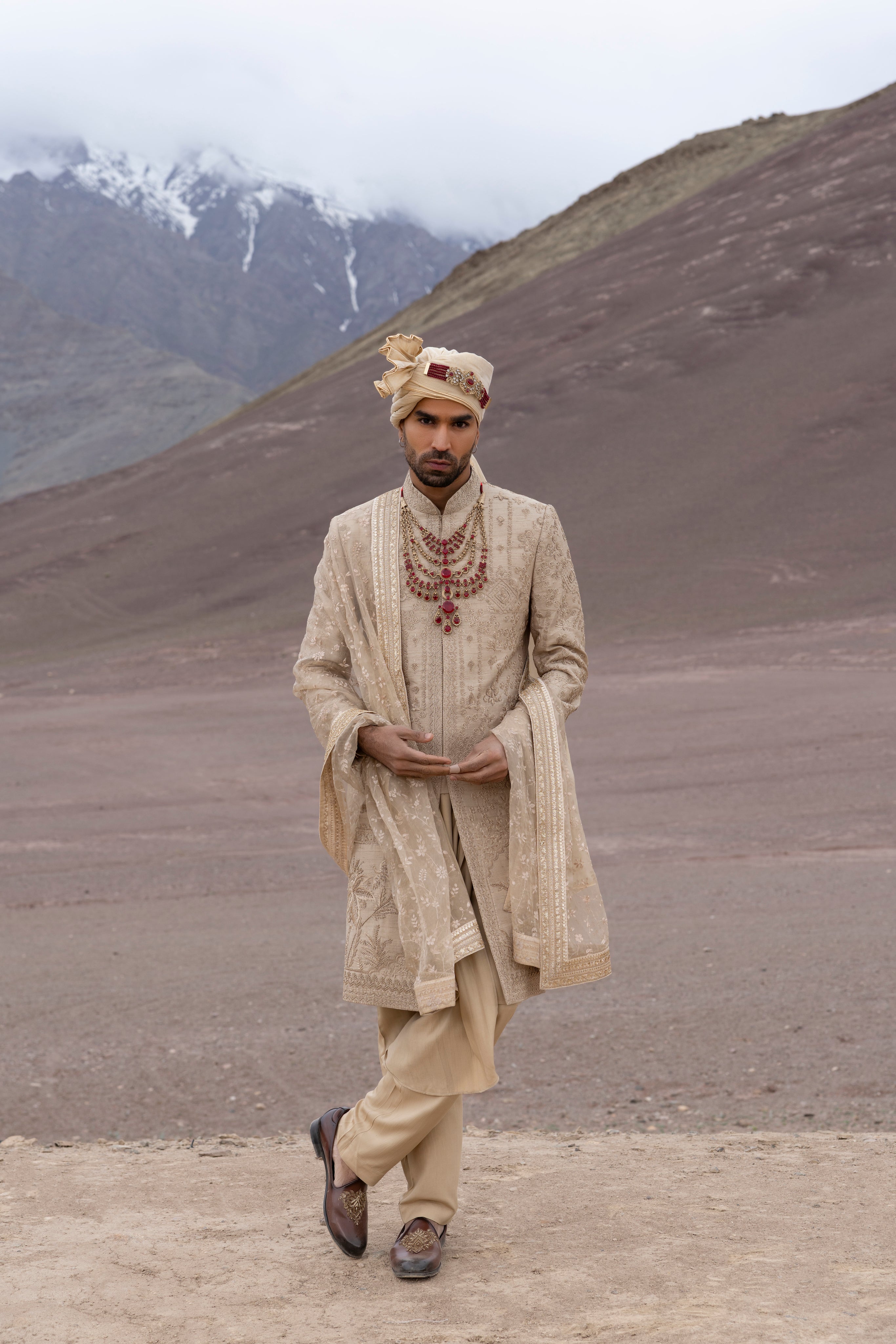 Gold raw silk sherwani with intricate hand-embroidery paired with a modal kurta pyjama & an embroidered georgette stole.