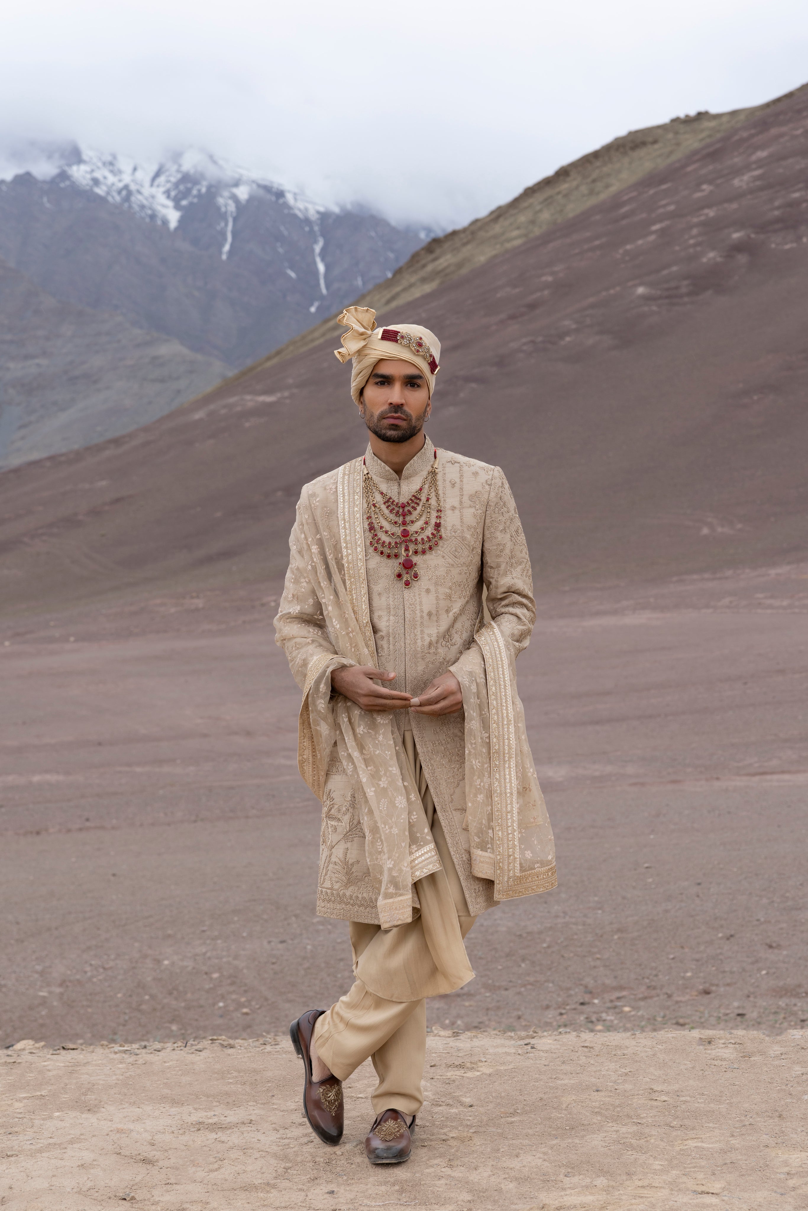 Gold raw silk sherwani with intricate hand-embroidery paired with a modal kurta pyjama & an embroidered georgette stole.