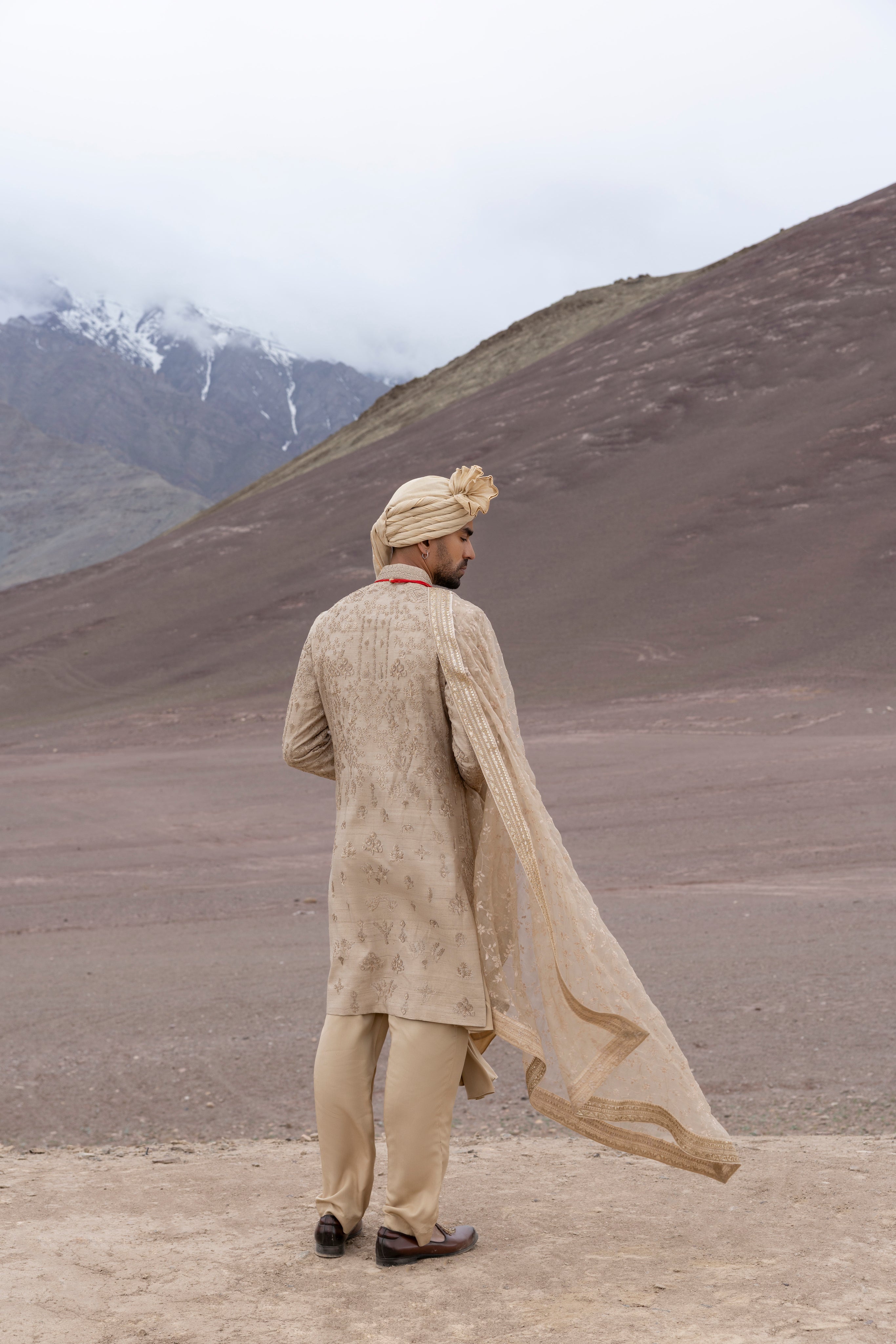 Gold raw silk sherwani with intricate hand-embroidery paired with a modal kurta pyjama & an embroidered georgette stole.