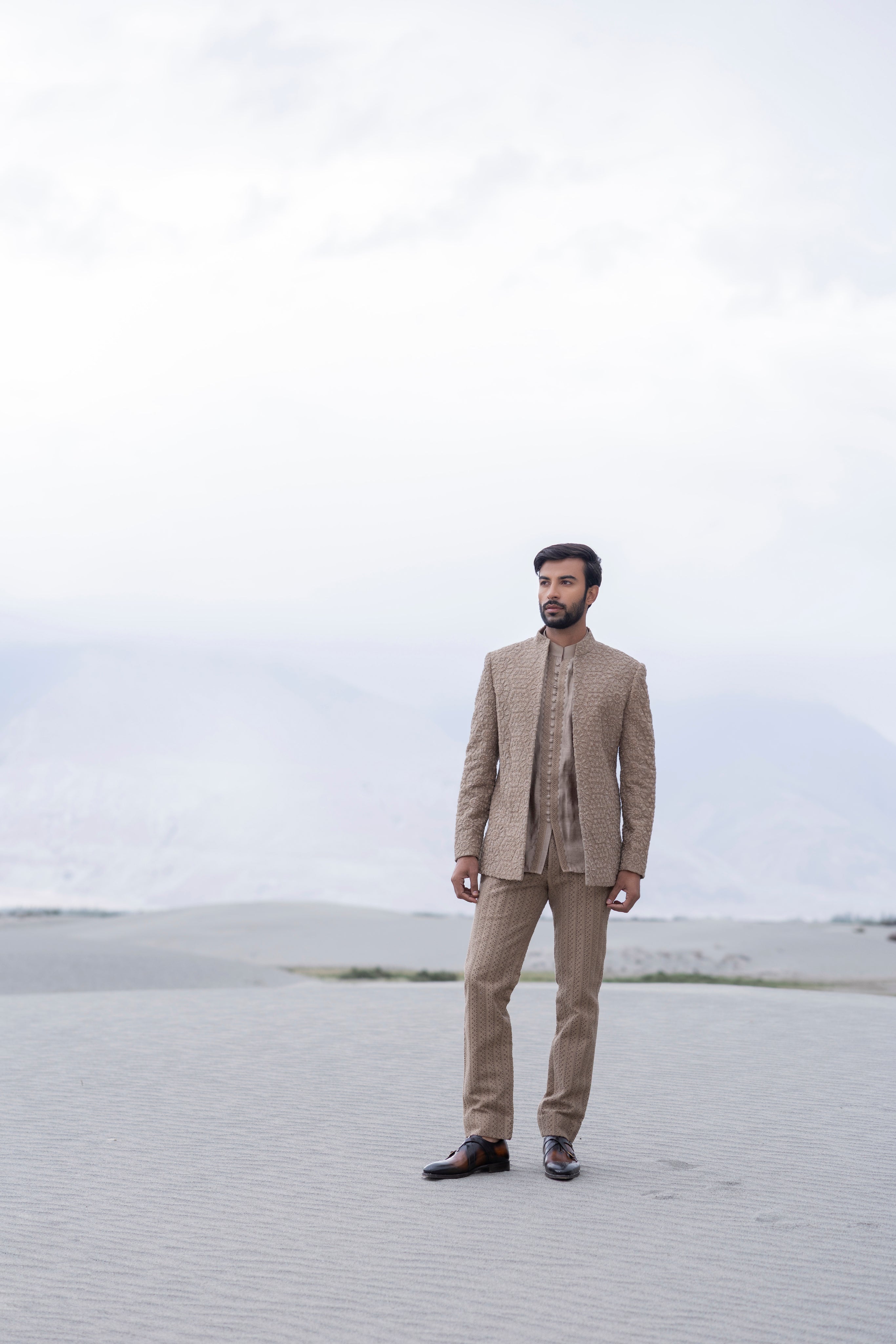 khakhi crochet hand-embroidered open indowestern jacket paired with a short kurta and pants with crochet detailing.