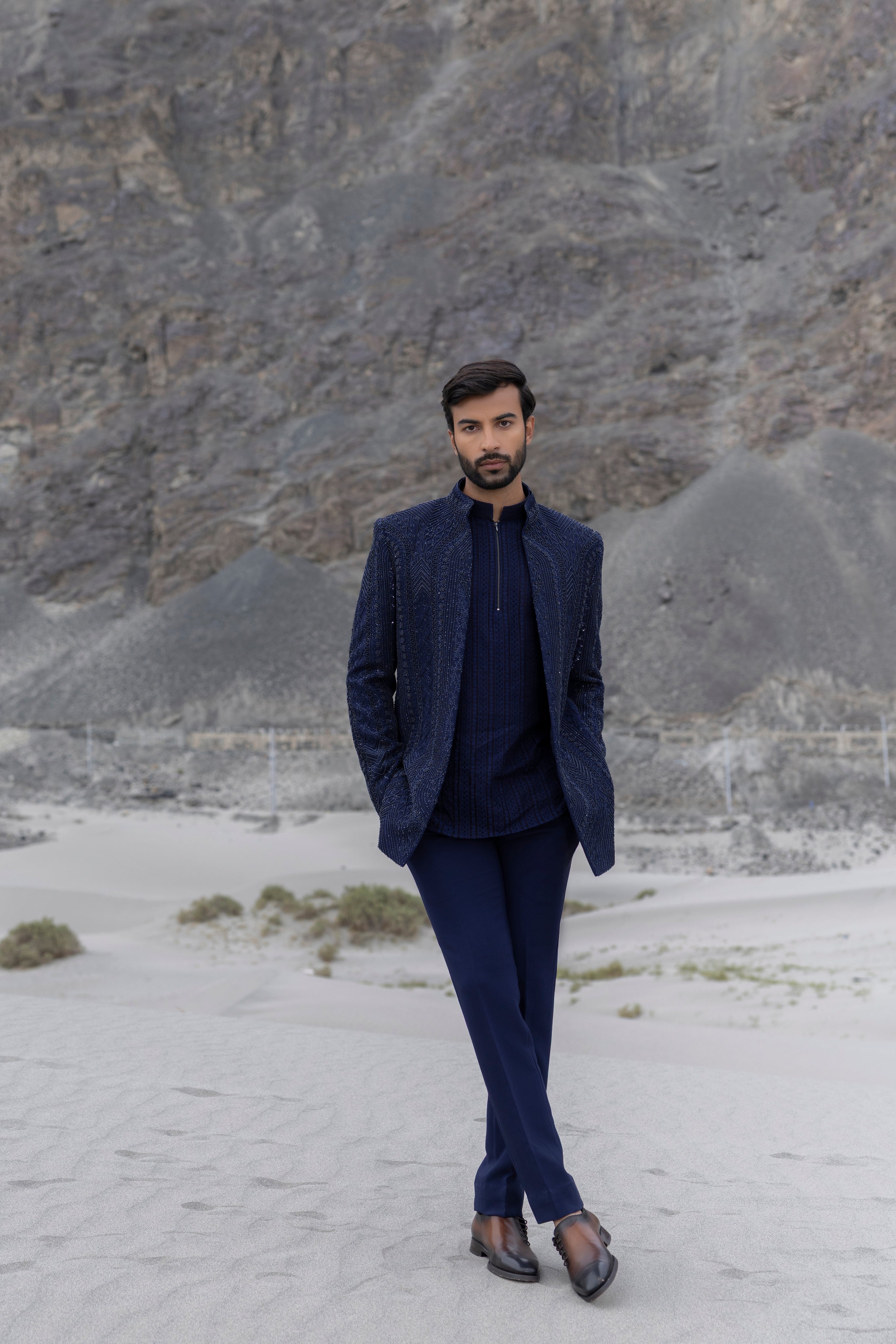 Navy Blue front open short indowestern jacket with monotone hand-embroidery paired with a crochet kurtawith zipper detailing  and a pant.