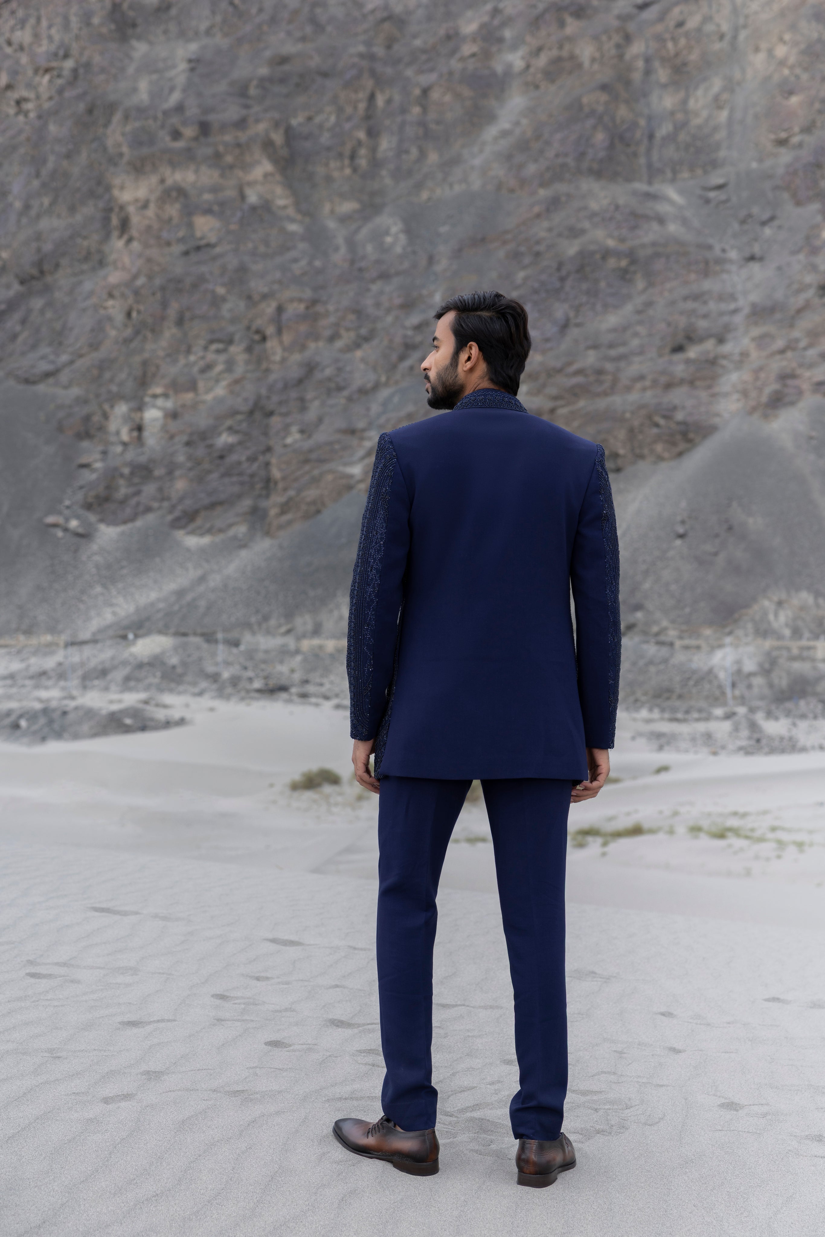 Navy Blue front open short indowestern jacket with monotone hand-embroidery paired with a crochet kurtawith zipper detailing  and a pant.