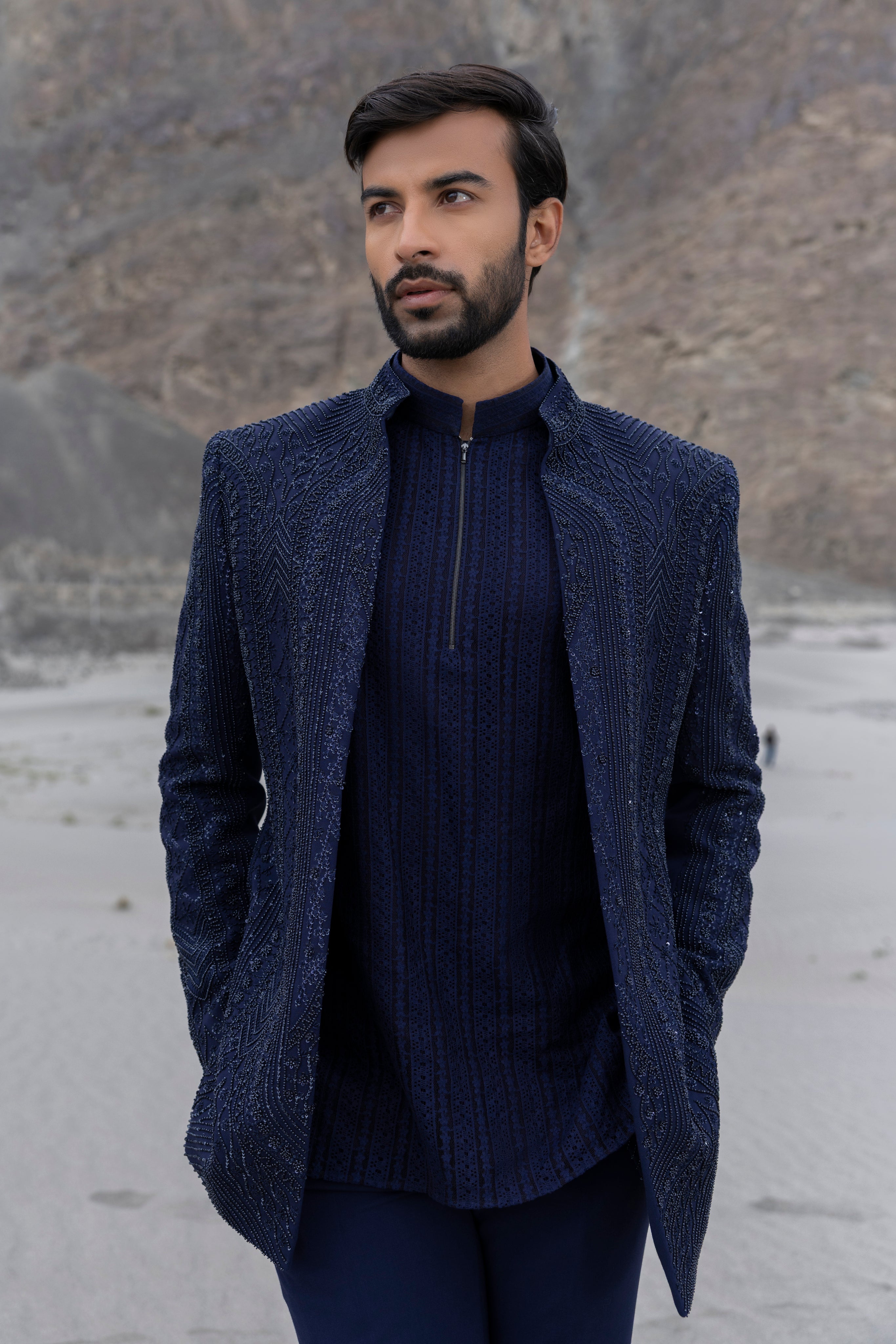 Navy Blue front open short indowestern jacket with monotone hand-embroidery paired with a crochet kurtawith zipper detailing  and a pant.