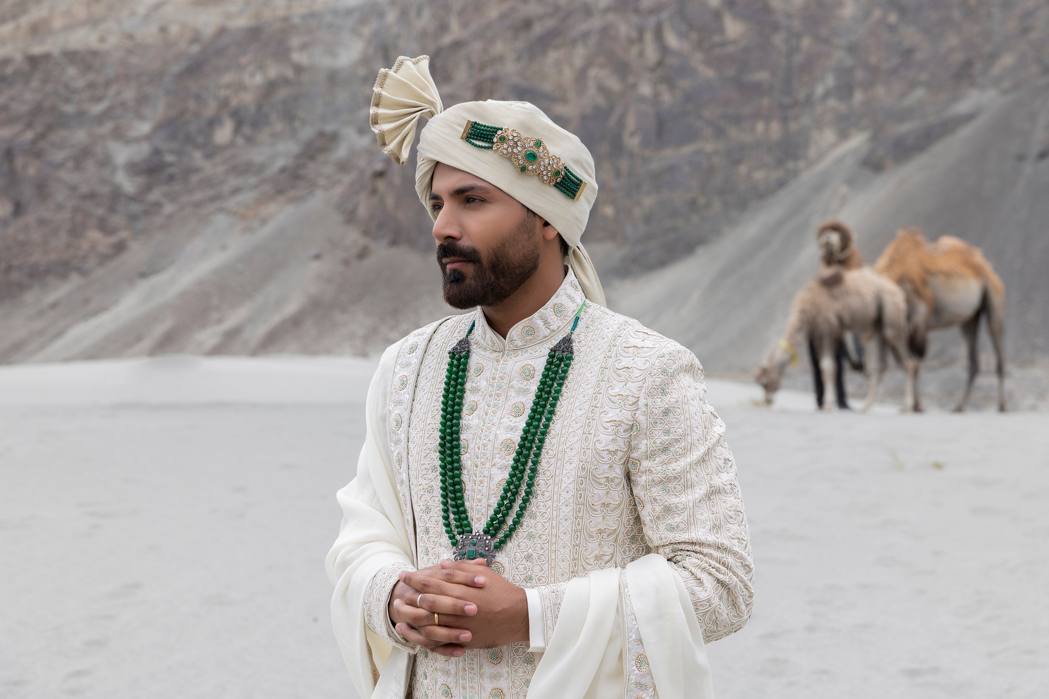 Off-white raw silk sherwani with intricate hand-embroidery paired with a modal kurta pyjama & an organza stole.