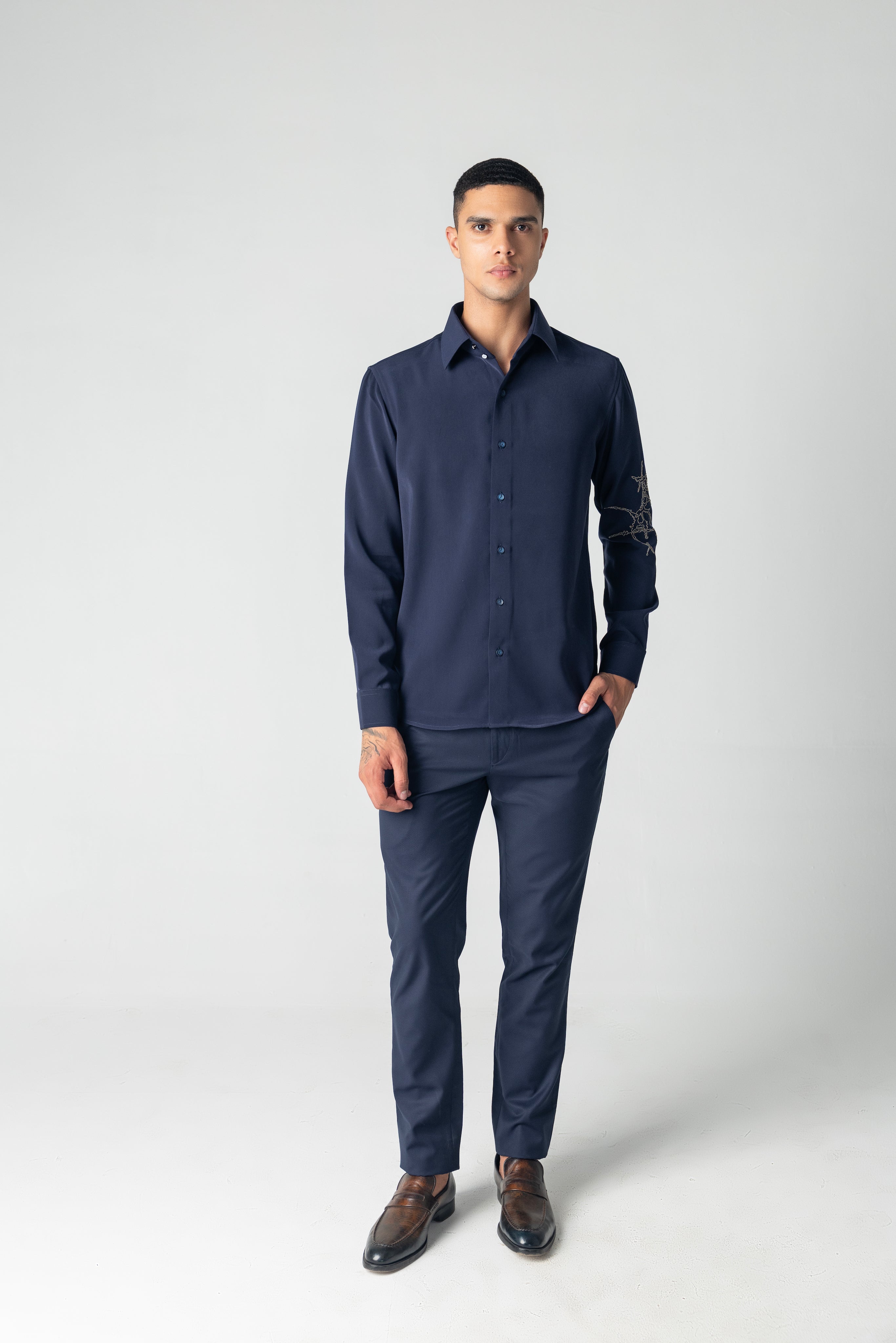 Navy blue shirt with hand-embroidered metallic motif on sleeve