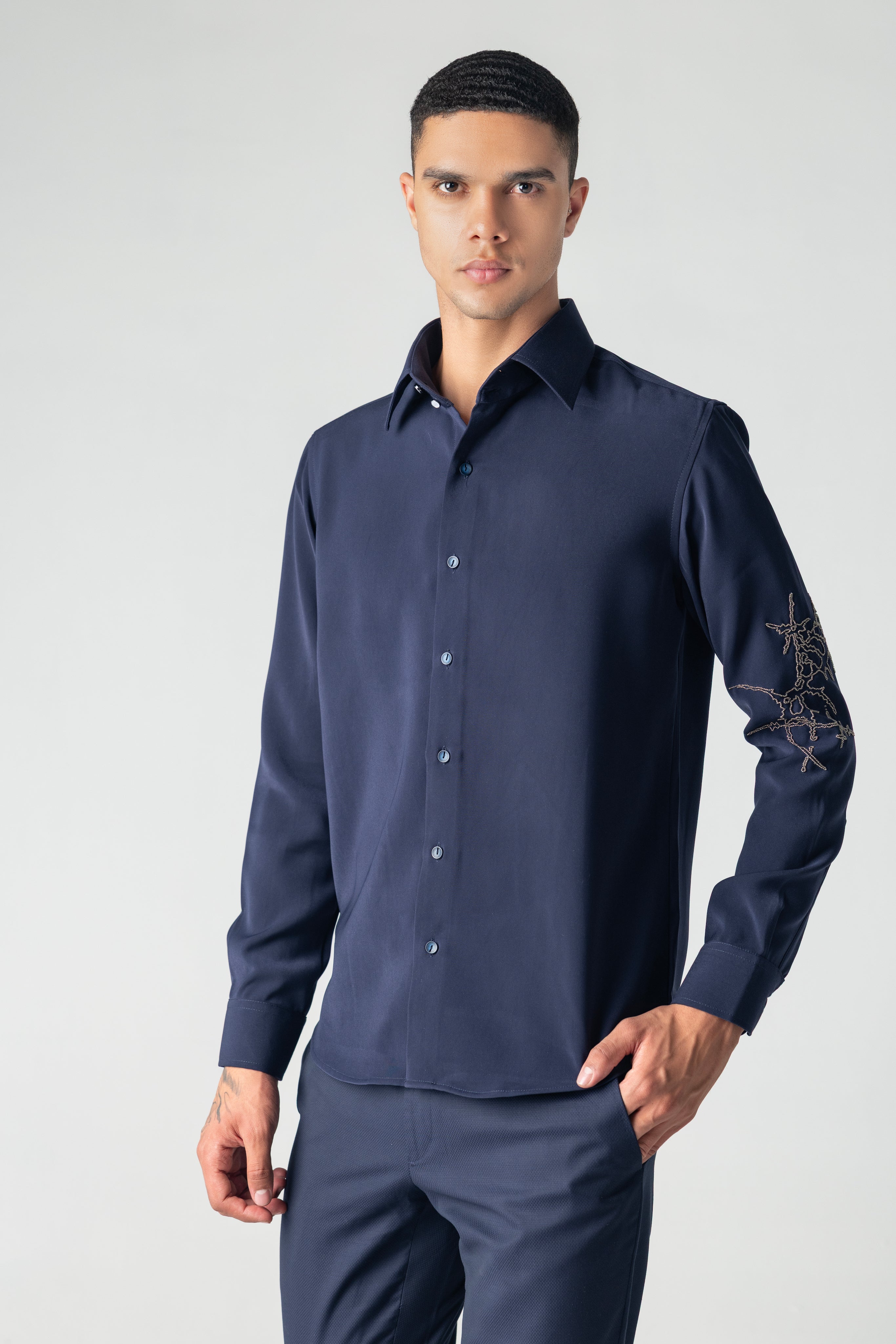 Navy blue shirt with hand-embroidered metallic motif on sleeve