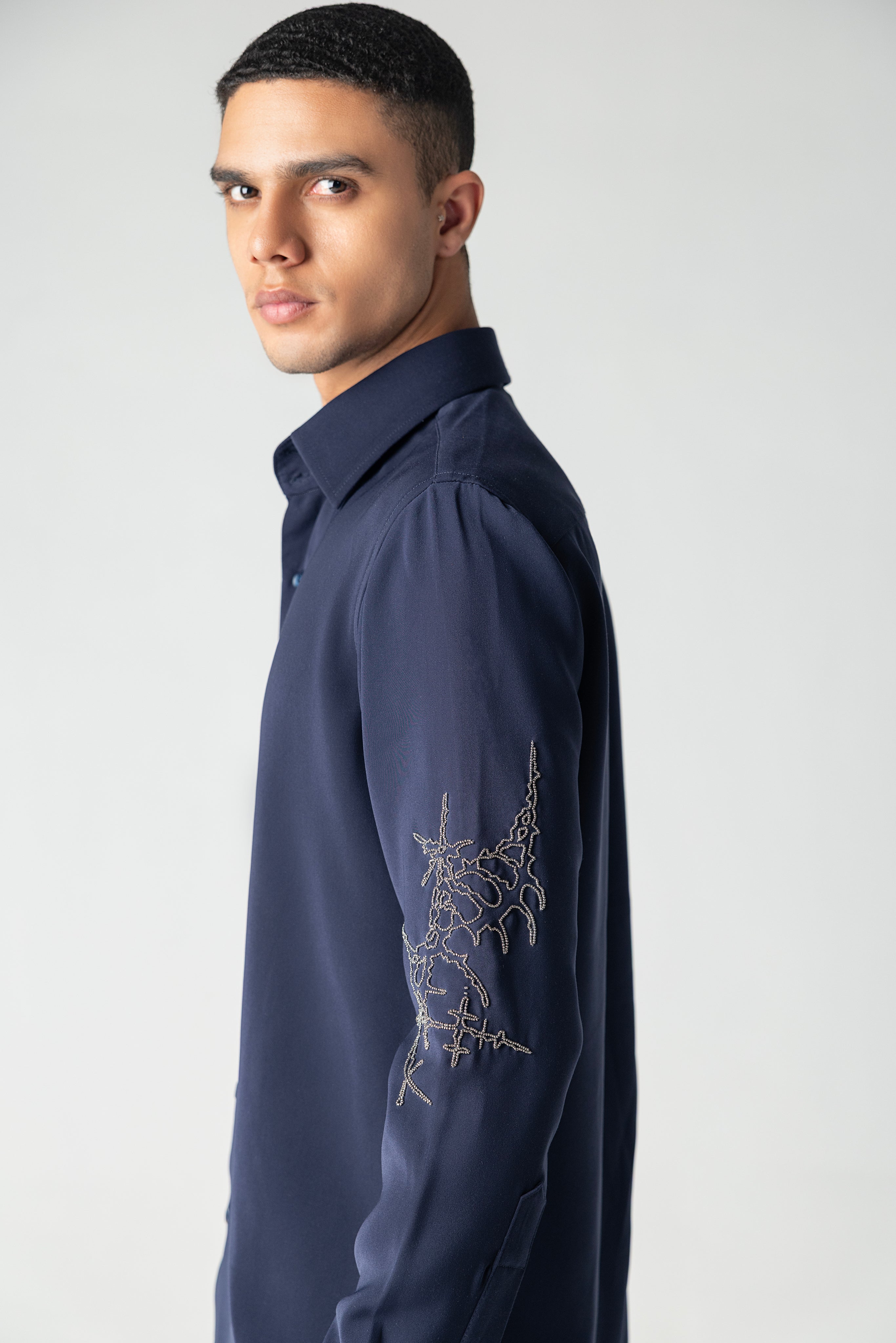 Navy blue shirt with hand-embroidered metallic motif on sleeve