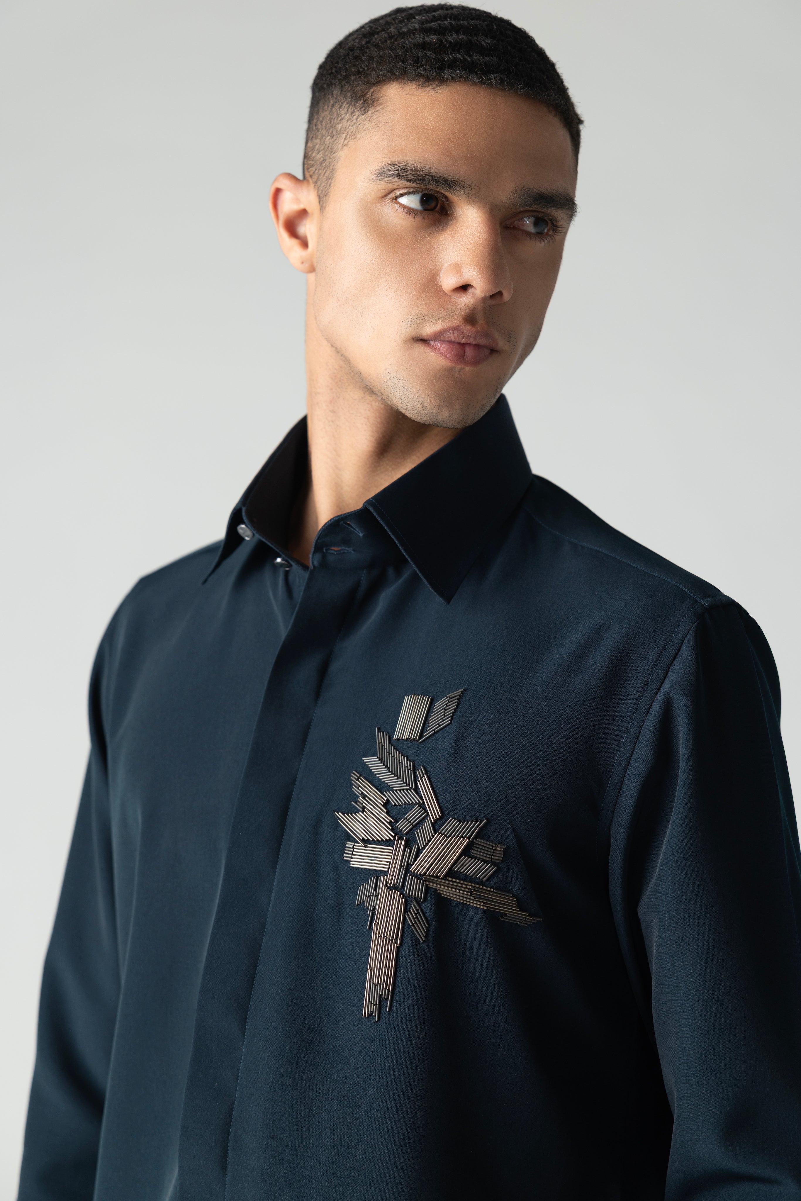 Turquoise shirt with hand-embroidered metal motif