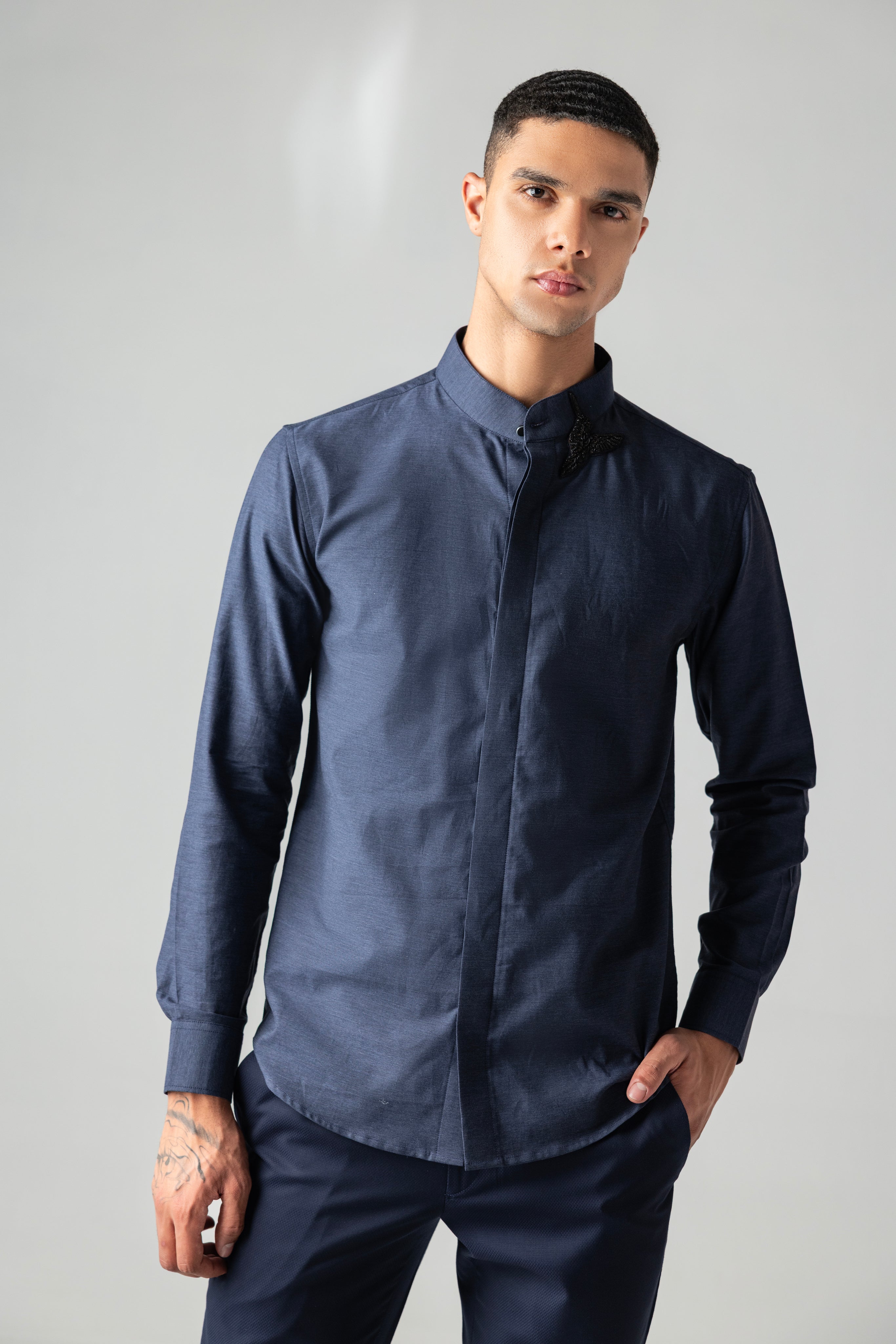 Blue knit shirt with hand-embroidered bird motif on Mandarin collar