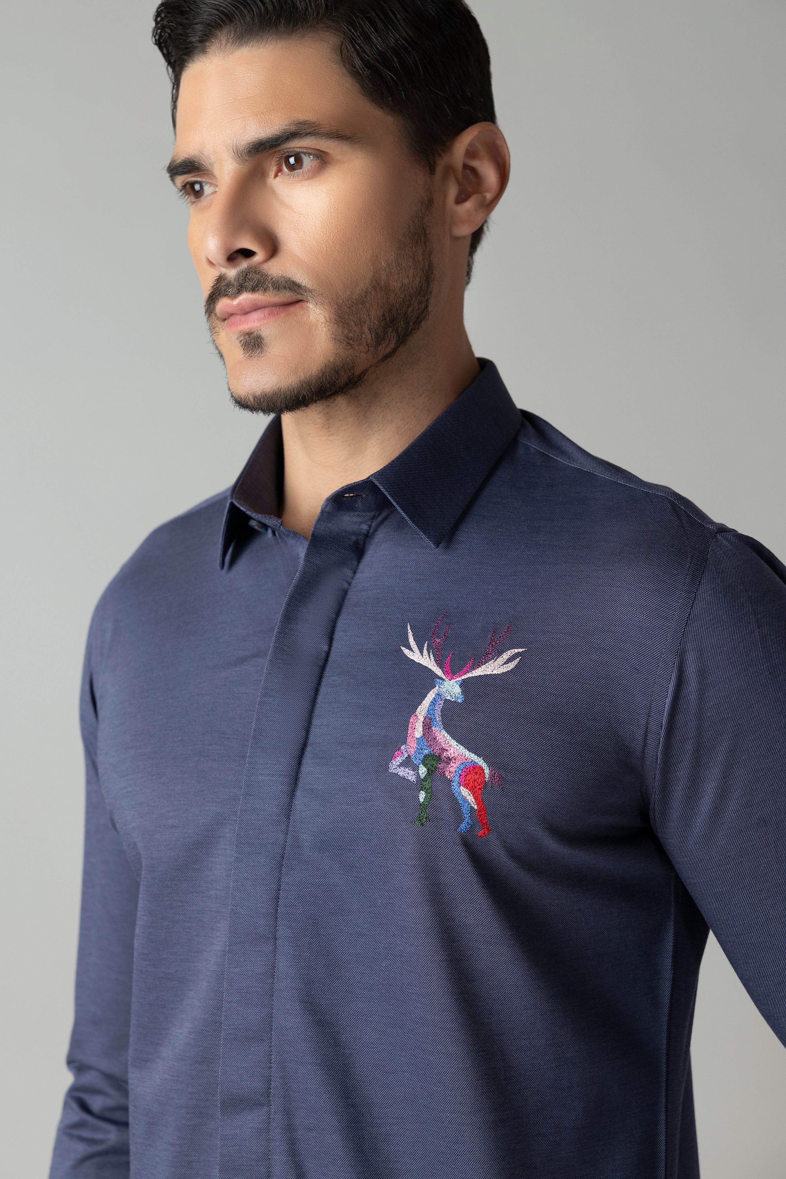 Navy blue knit shirt with embroidered multi-coloured Reindeer motif