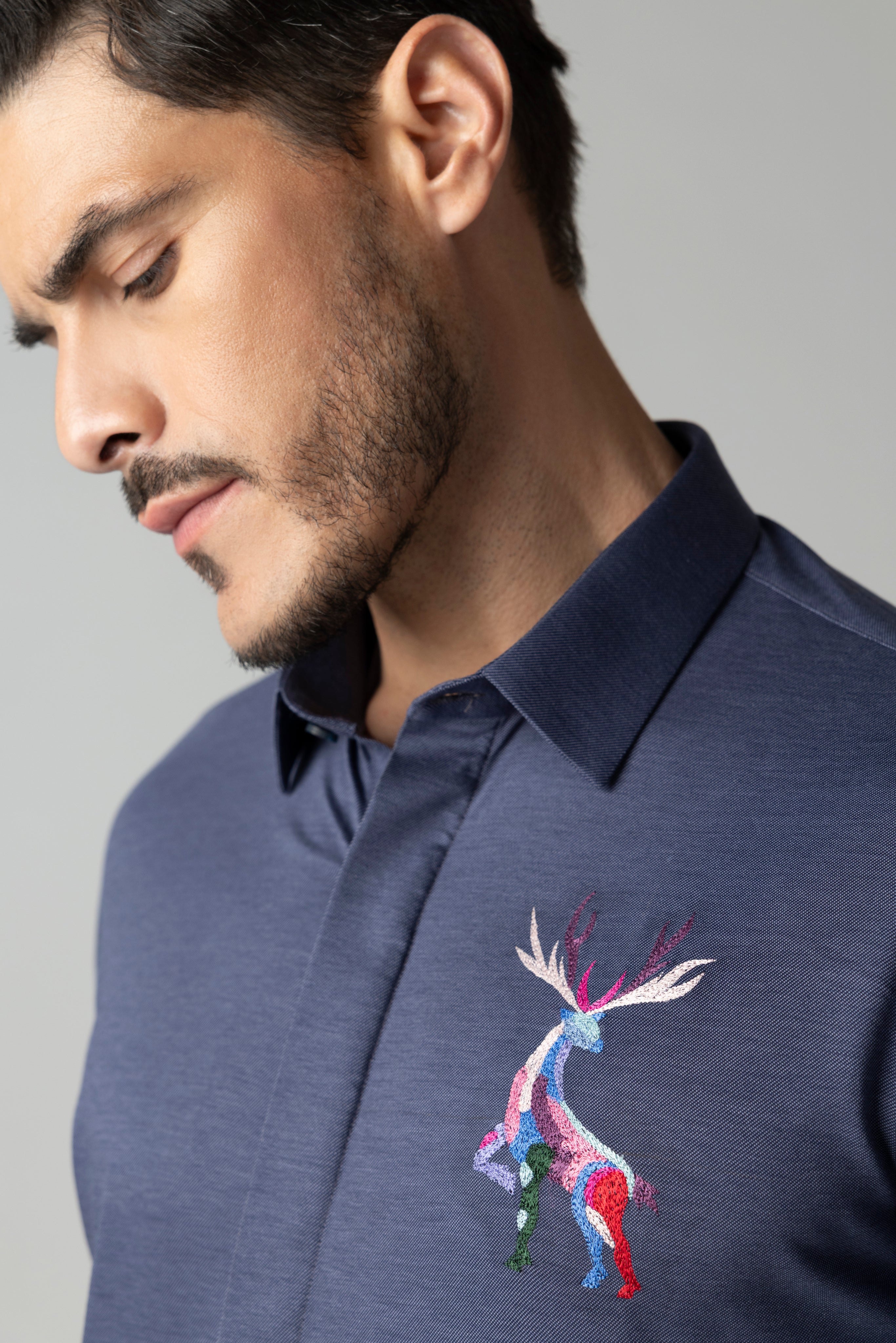 Navy blue knit shirt with embroidered multi-coloured Reindeer motif