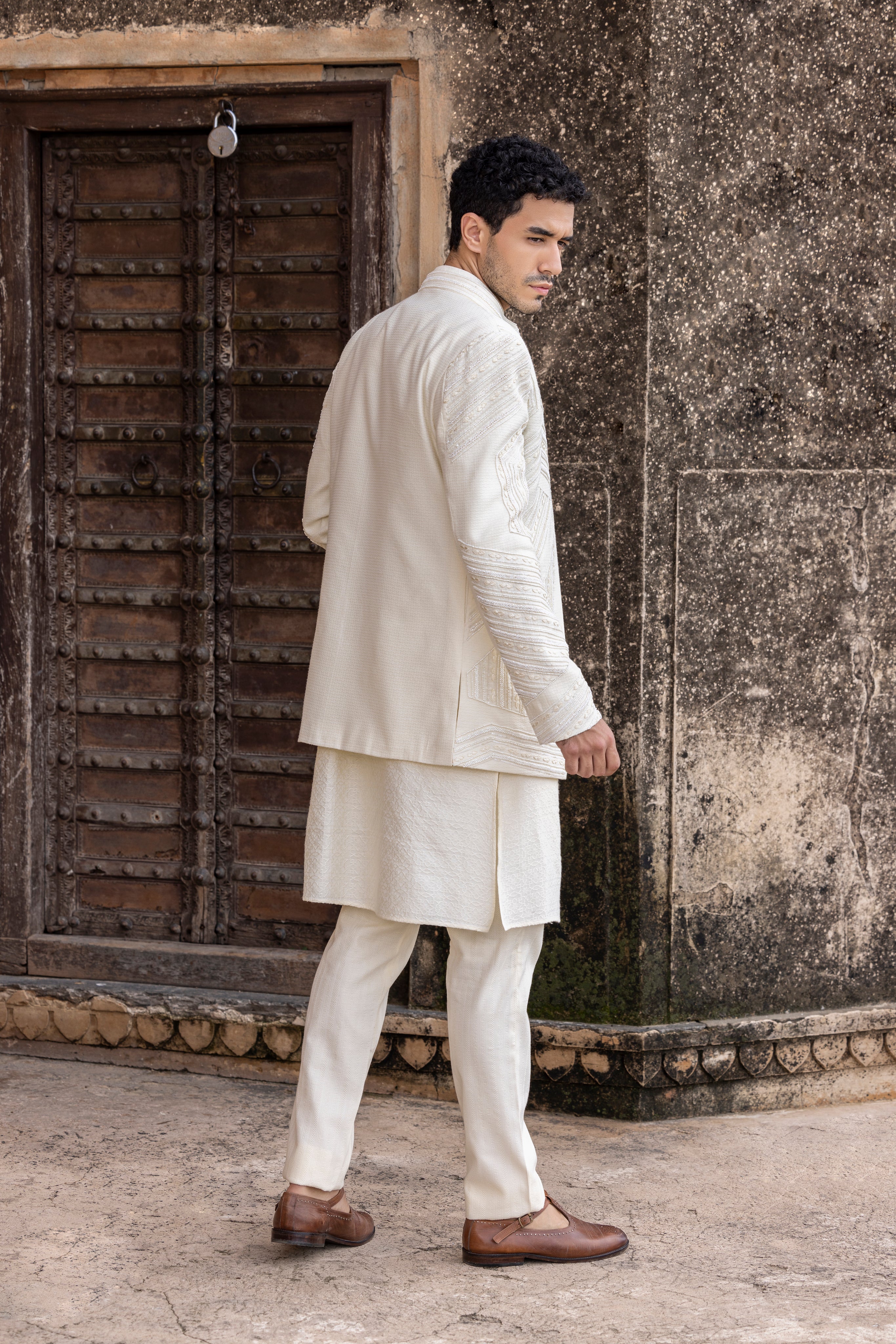 Ivory front-open indowestern jacket highlighted with intricate hand embroidery in geometrical patterns, paired with kurta and pants.