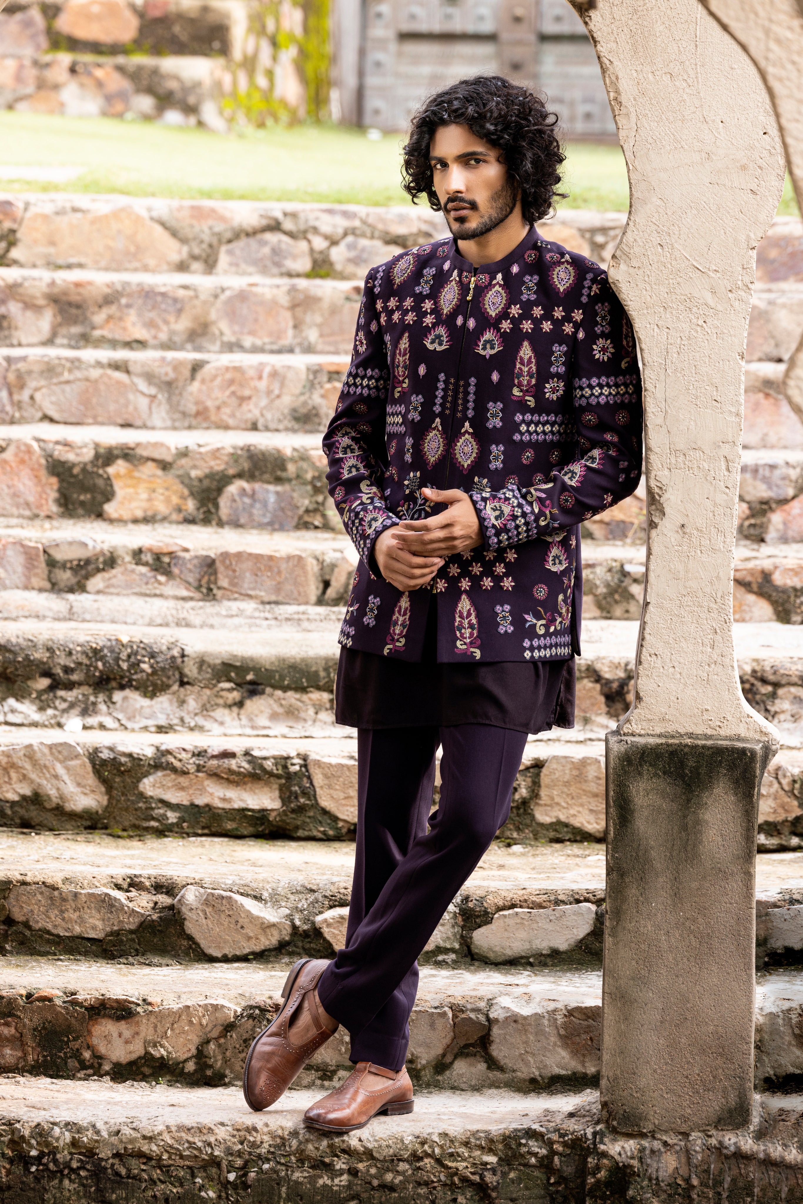 Wine indowestern jacket embellished with multicoloured hand embroidered motifs paired with matching kurta and pants.